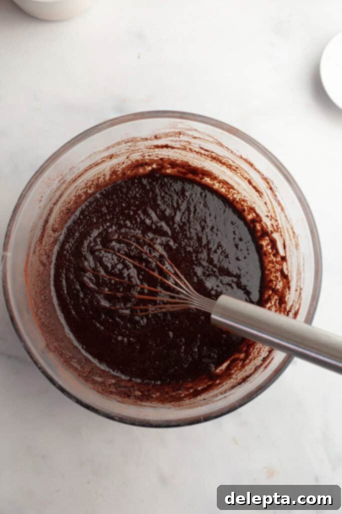 Decadent One Bowl Fudgy Brown Butter Espresso Brownies 6 Smooth, glossy brownie batter in a glass bowl after adding cocoa powder and eggs, being whisked.
