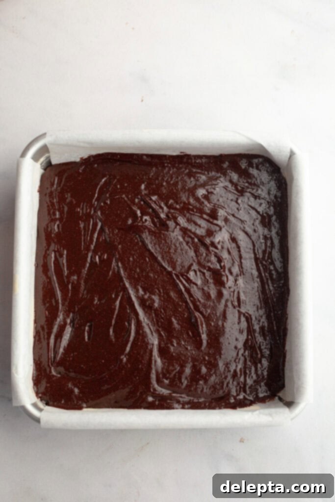 Decadent One Bowl Fudgy Brown Butter Espresso Brownies 8 Unbaked brownie batter evenly spread in a parchment-lined 8x8 square baking pan, ready for the oven.