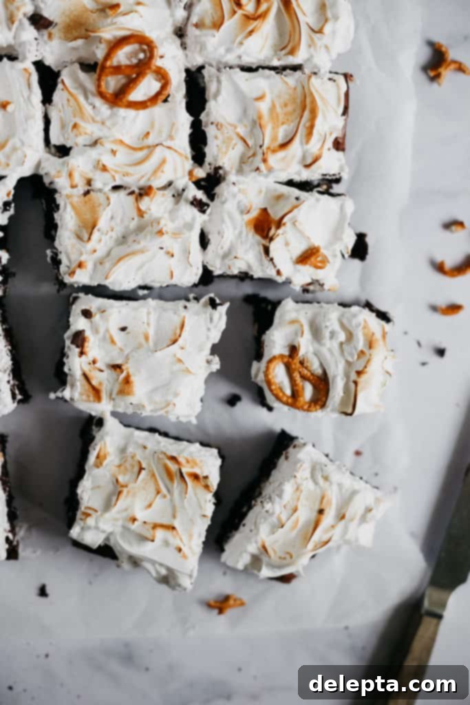 Fireside S'mores Brownies 5 Close-up of neatly cut slices of campfire brownies, showing the thick, fudgy base, pretzel pieces, and airy marshmallow topping