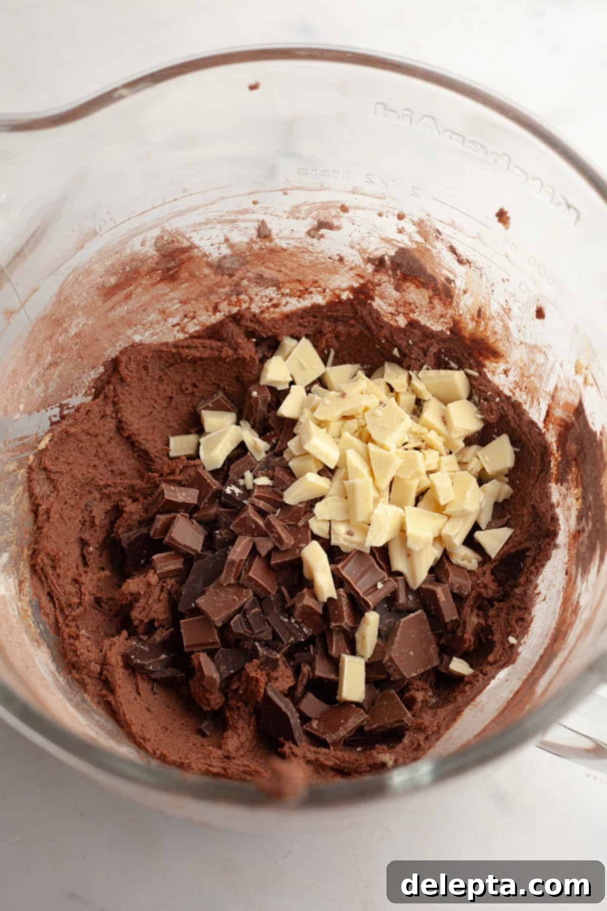 Chewy Triple Chocolate Chunk One Bowl Cookies 6 Chocolate cookie dough in a glass bowl with freshly chopped chocolate pieces folded in.