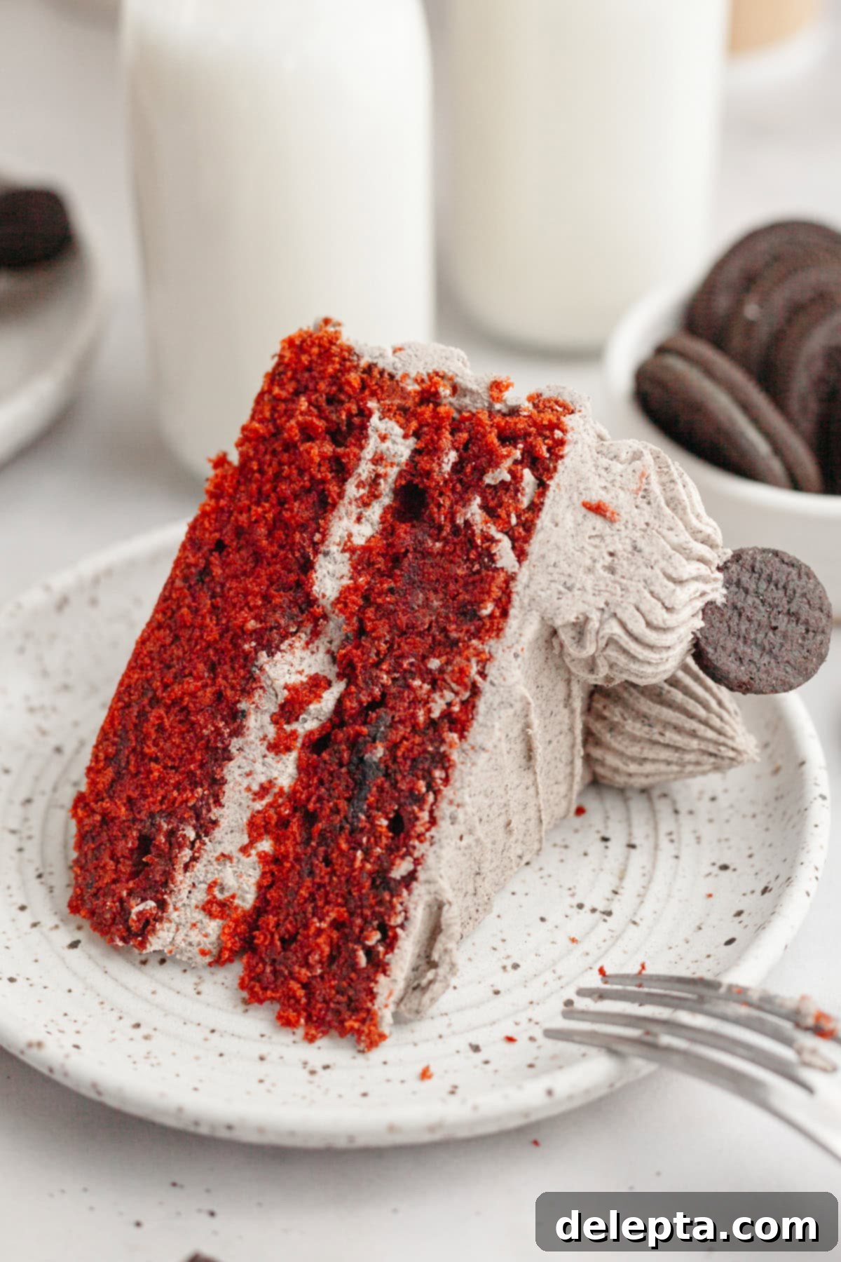 Red Velvet Oreo Cake with Oreo Buttercream 13 A beautifully presented slice of red velvet cake with Oreo frosting on a small white plate, ready for dessert.