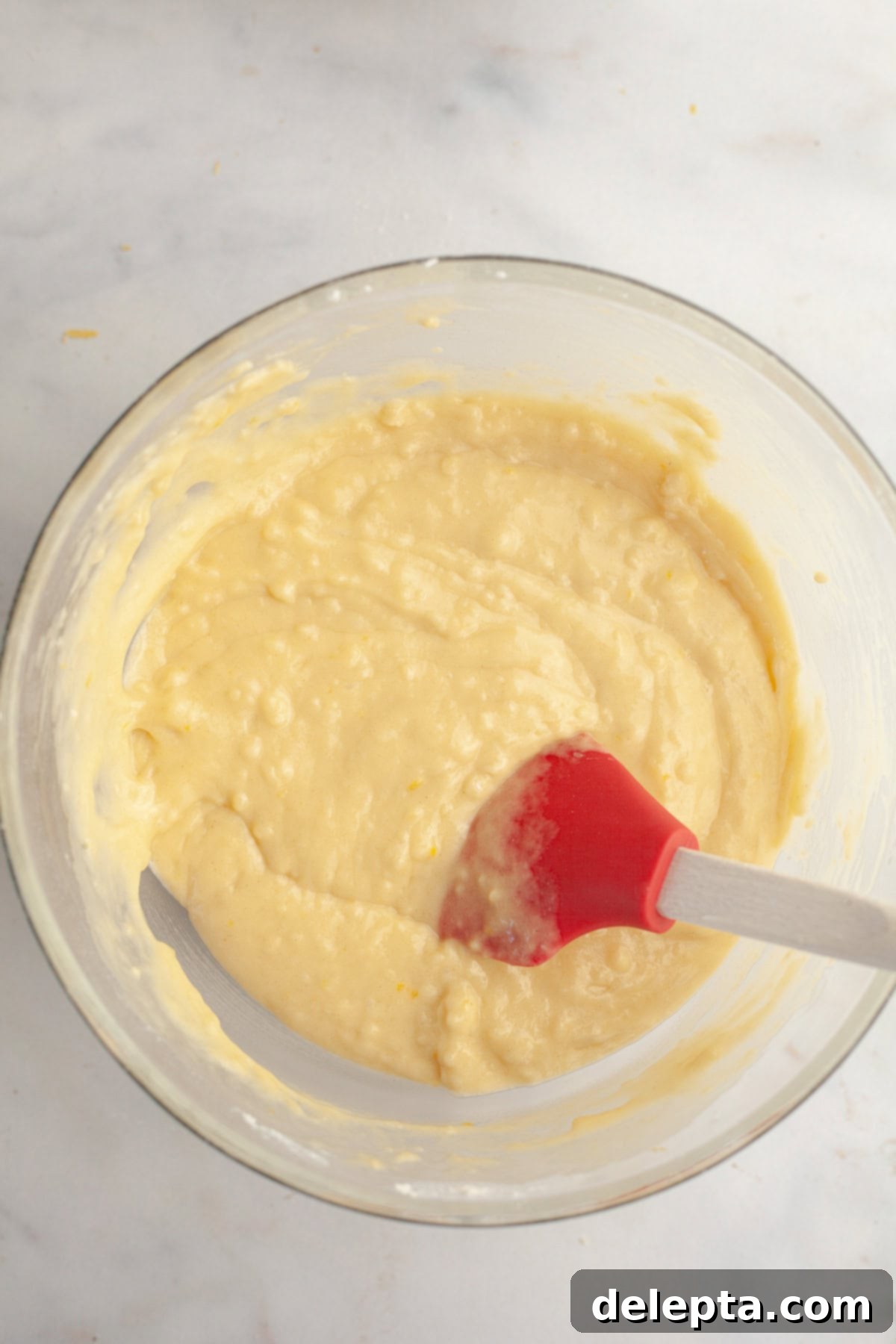 Simple One-Bowl Strawberry Snack Cake 5 Vanilla cake batter in a glass bowl with a rubber spatula.