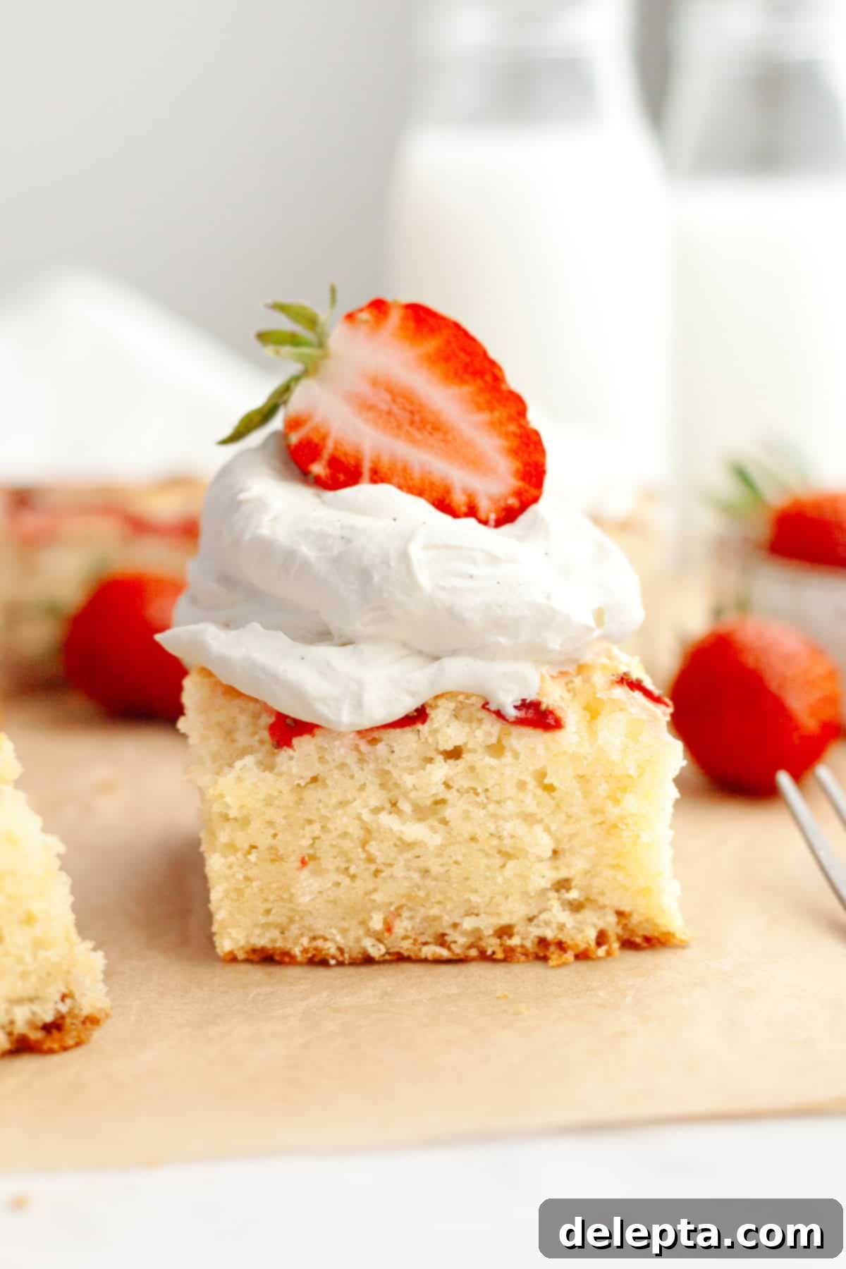 Simple Homemade Vanilla Bean Whipped Cream 5 A close up of a slice of a mini strawberry cake, topped with homemade vanilla bean whipped cream and half of a fresh strawberry, showcasing its perfect pairing.