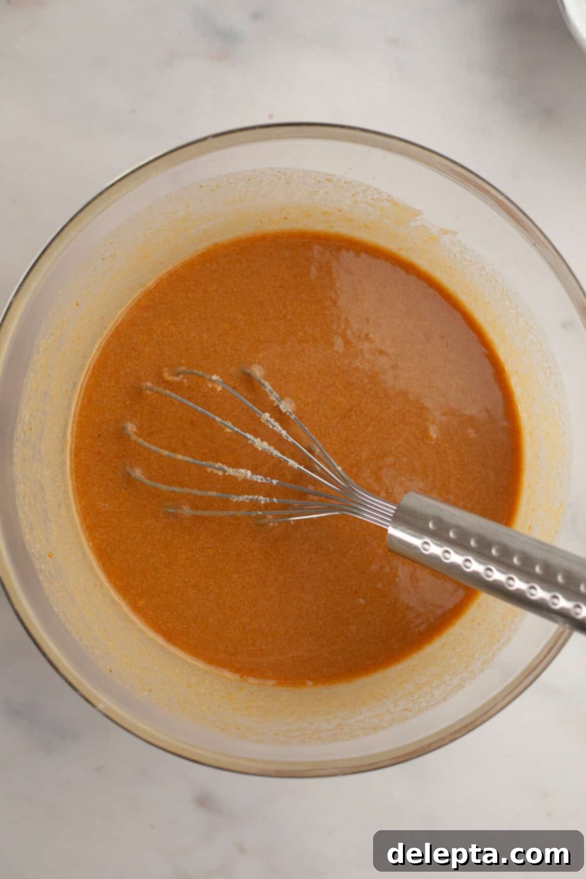 One Bowl Brown Butter Peanut Butter Oreo Perfection 5 A light brown liquid in a glass bowl with a whisk.