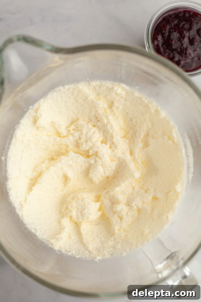 Berry Vanilla Mascarpone Bliss 4 A large glass mixing bowl with creamed butter, sugar, and oil, showing a light and fluffy texture.
