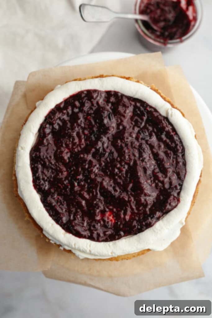 Berry Vanilla Mascarpone Bliss 10 A vanilla cake layer with a neat ring of white mascarpone frosting piped around the edges, and the center generously filled with a vibrant mixed berry compote.