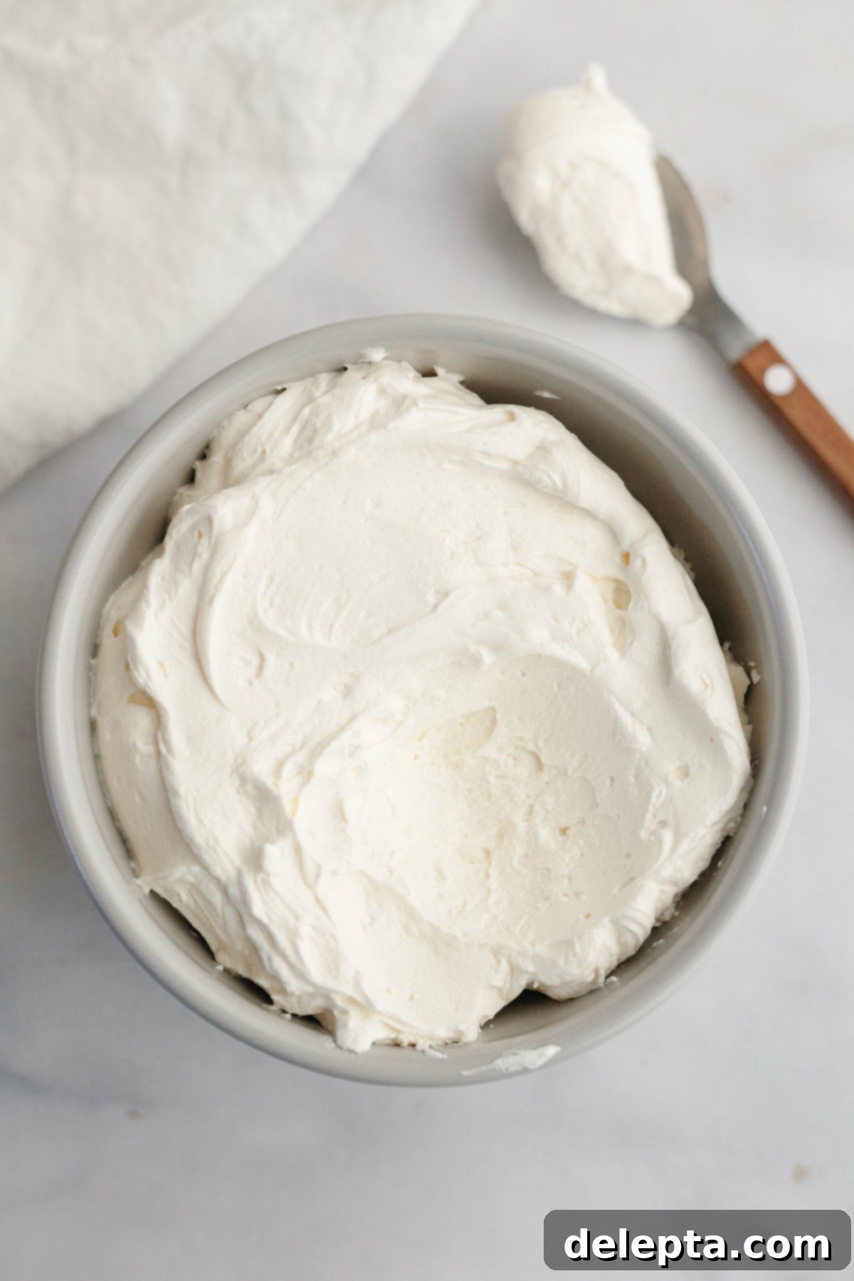 Dreamy 5-Ingredient Mascarpone Whipped Cream Frosting 2 A small grey bowl filled with mascarpone whipped cream frosting.