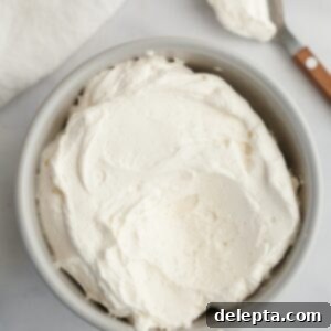 Dreamy 5-Ingredient Mascarpone Whipped Cream Frosting 10 A light grey bowl filled with mascarpone whipped cream frosting.
