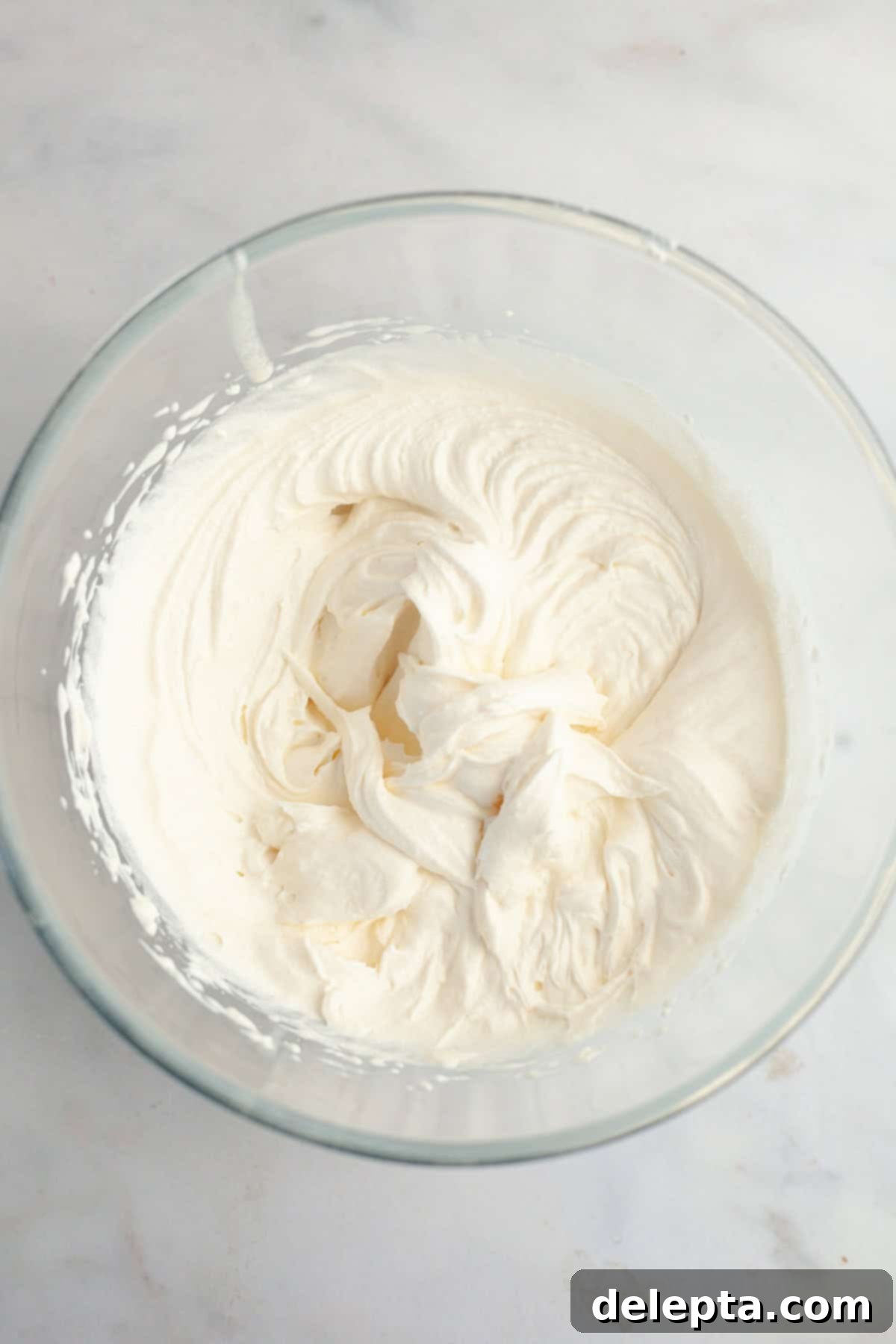 Dreamy 5-Ingredient Mascarpone Whipped Cream Frosting 5 A large glass bowl filled with mascarpone whipped cream frosting.
