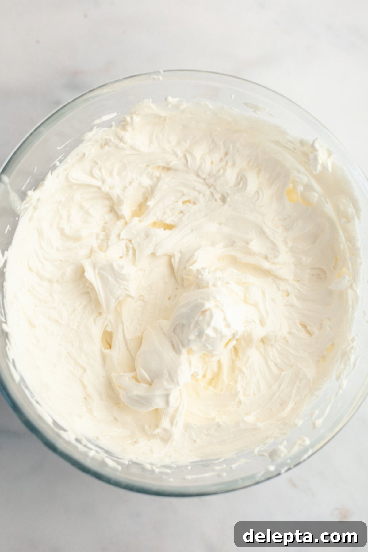 Dreamy 5-Ingredient Mascarpone Whipped Cream Frosting 7 A large glass bowl filled with mascarpone whipped cream frosting.