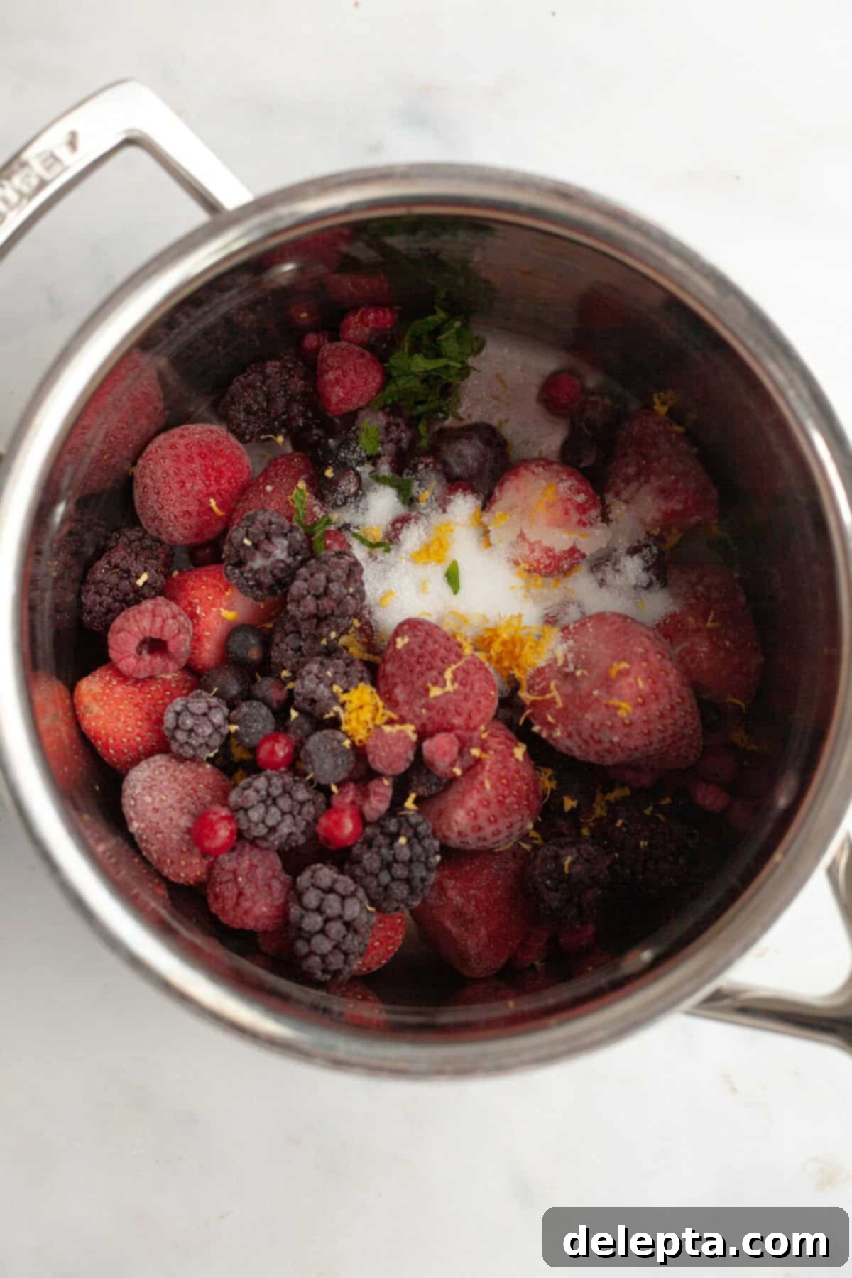Quick Berry Compote with Frozen Fruit 4 A silver saucepan filled with frozen mixed berries, lemon zest, and sliced up mint leaves.