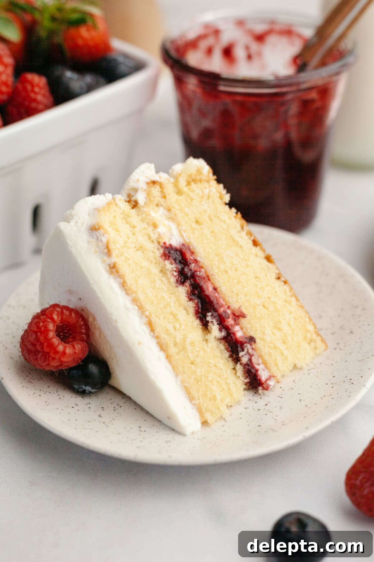 Quick Berry Compote with Frozen Fruit 7 A slice of berries and cream cake on a plate. The cake has white frosting and a mixed berry jam filling.