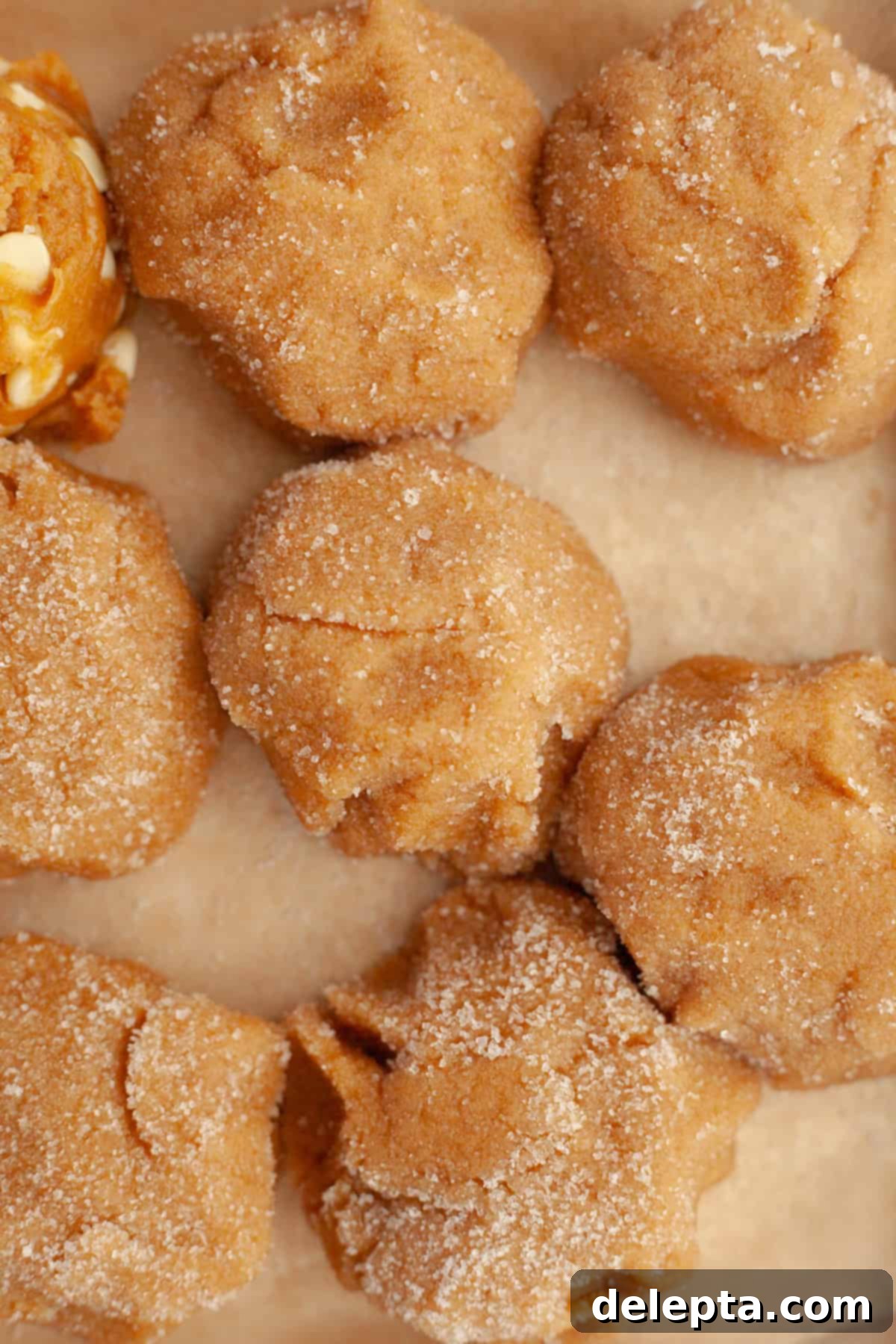 Golden Brown Butter Peanut Butter Cookies Ready Now 8 Perfectly scooped peanut butter cookie dough balls, generously rolled in white granulated sugar and arranged on parchment paper, ready for baking.