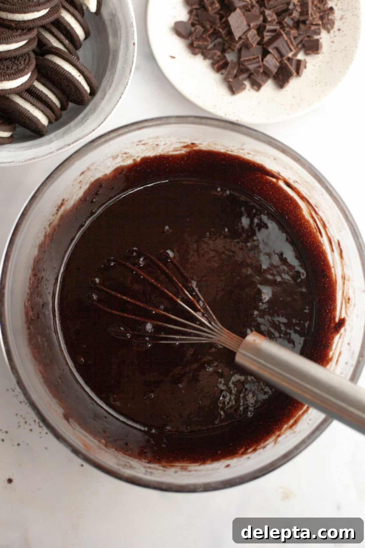 One-Bowl Decadence: Oreo Fudge Brownies 6 A large glass bowl filled with smooth, glossy brownie batter being whisked, indicating the emulsification stage.