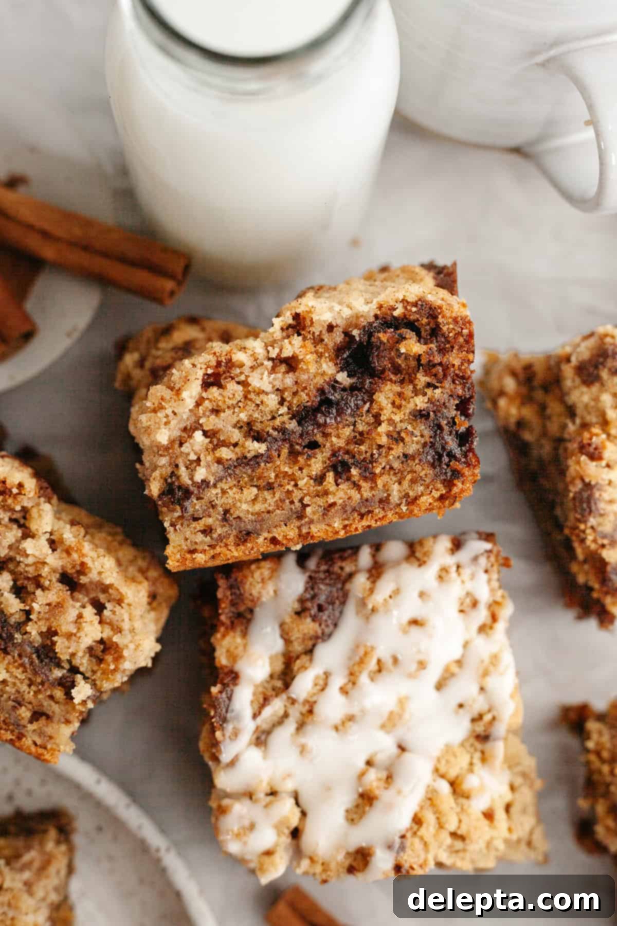 Perfectly Moist Banana Coffee Cake with Tangy Sour Cream 2 Square slices of banana coffee cake, generously drizzled with a sweet white glaze, on a white serving platter.