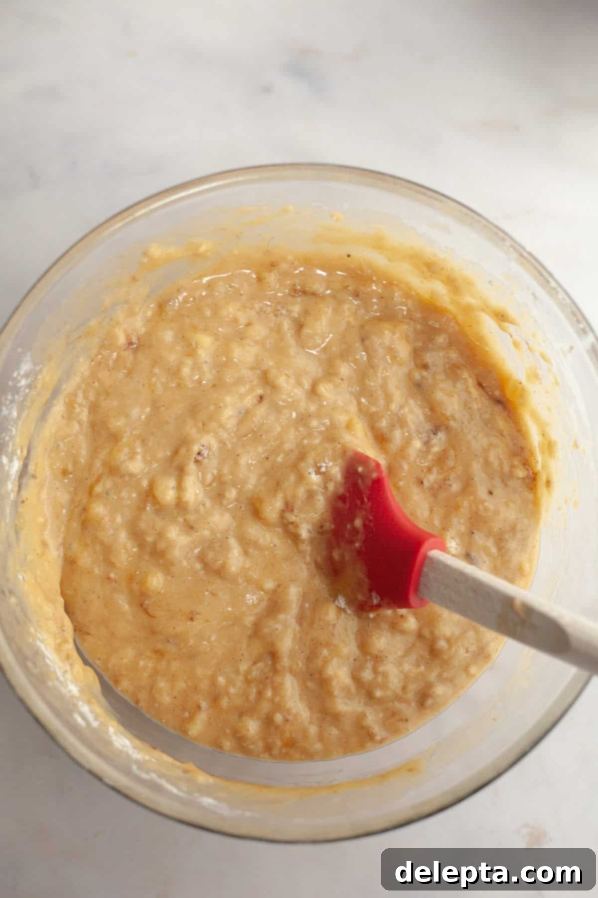 Perfectly Moist Banana Coffee Cake with Tangy Sour Cream 8 A large glass bowl with a rubber spatula and the banana bread batter, being gently folded.