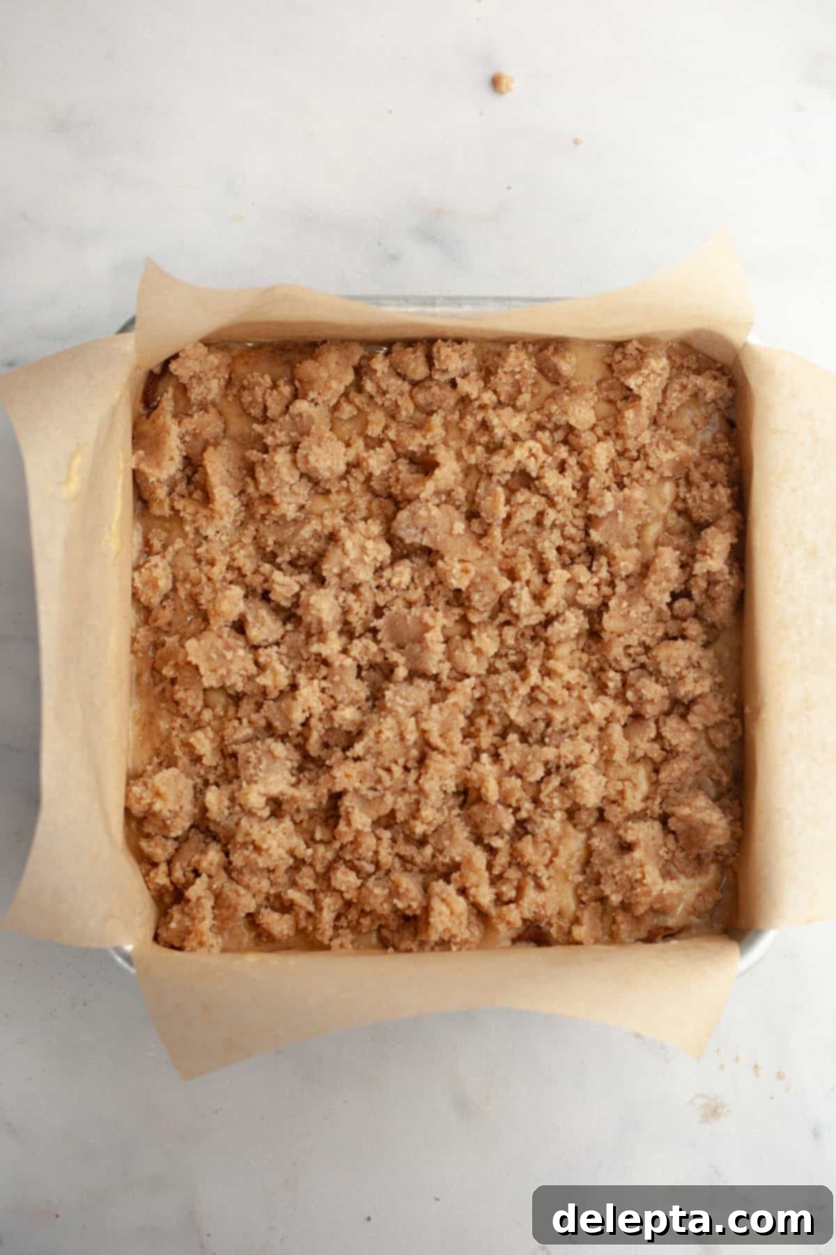 Perfectly Moist Banana Coffee Cake with Tangy Sour Cream 9 A square baking pan lined with parchment paper, filled with half the cake batter, topped with cinnamon filling, then the remaining batter and streusel.