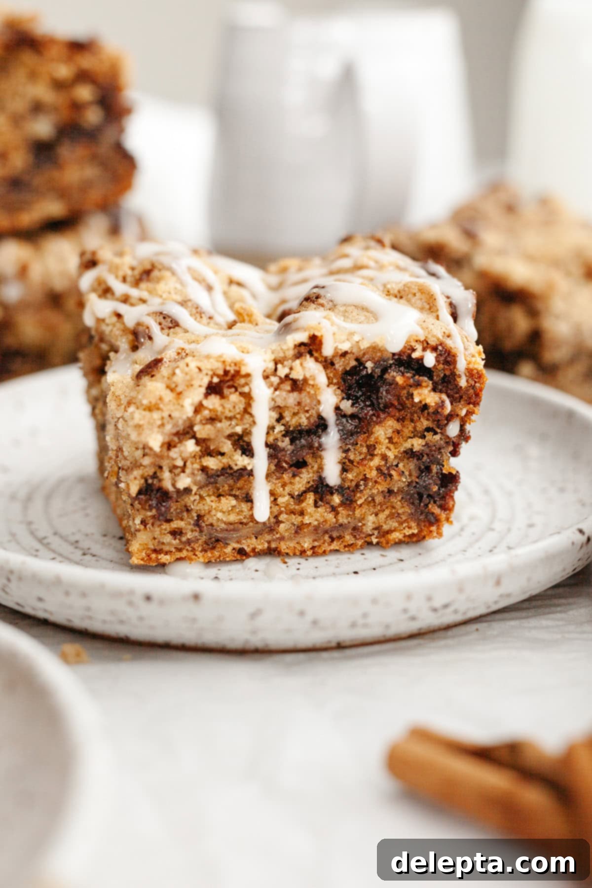 Perfectly Moist Banana Coffee Cake with Tangy Sour Cream 10 A beautifully baked slice of banana bread coffee cake, drizzled with a sweet white glaze, presented on a small ceramic plate.