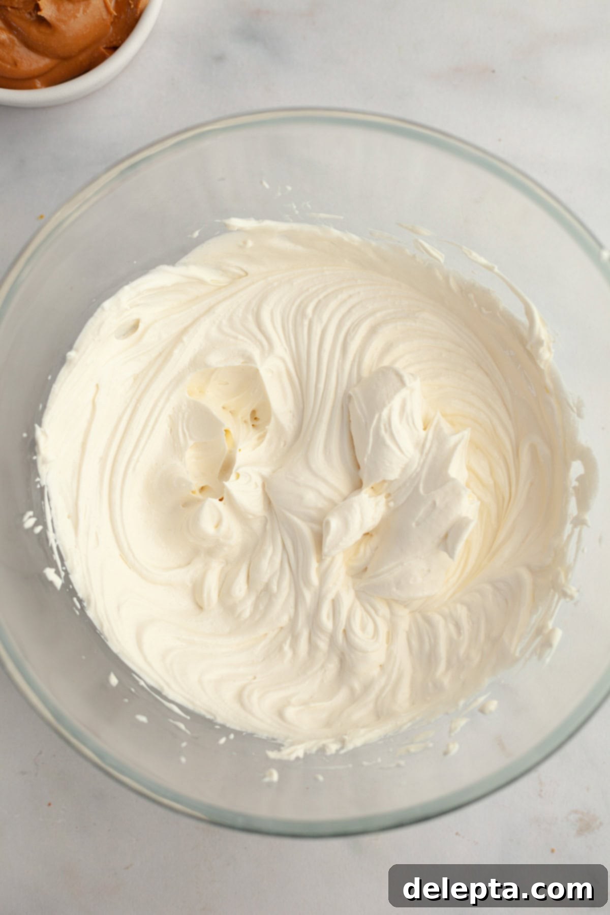 Banana Peanut Butter Bliss 8 Whipped heavy cream in a glass bowl, forming the base of the peanut butter cream cheese frosting.