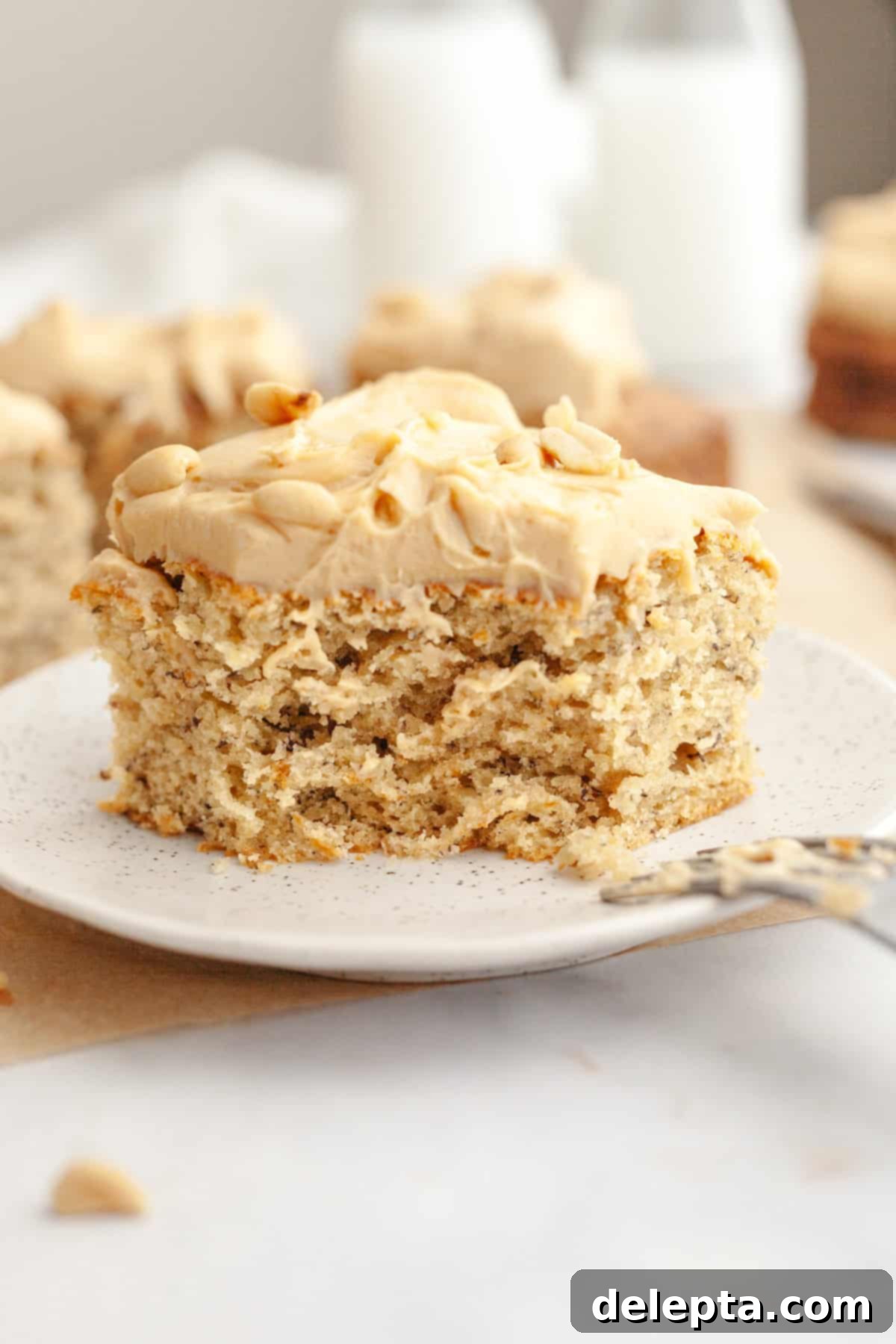 Banana Peanut Butter Bliss 10 A beautifully frosted slice of banana cake with peanut butter frosting on a small plate, ready to be enjoyed.