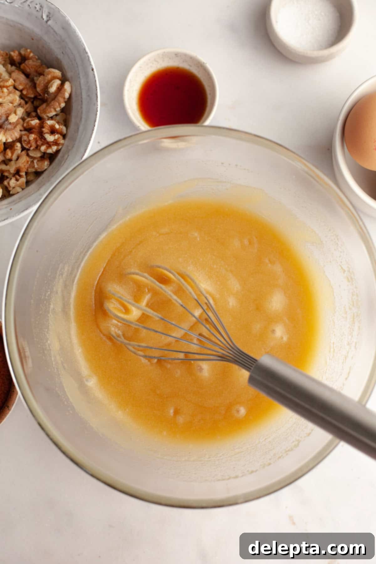 One Bowl Wonder Fudgy Walnut Brownies 4 A glass bowl with a whisk and a yellow mixture in it.