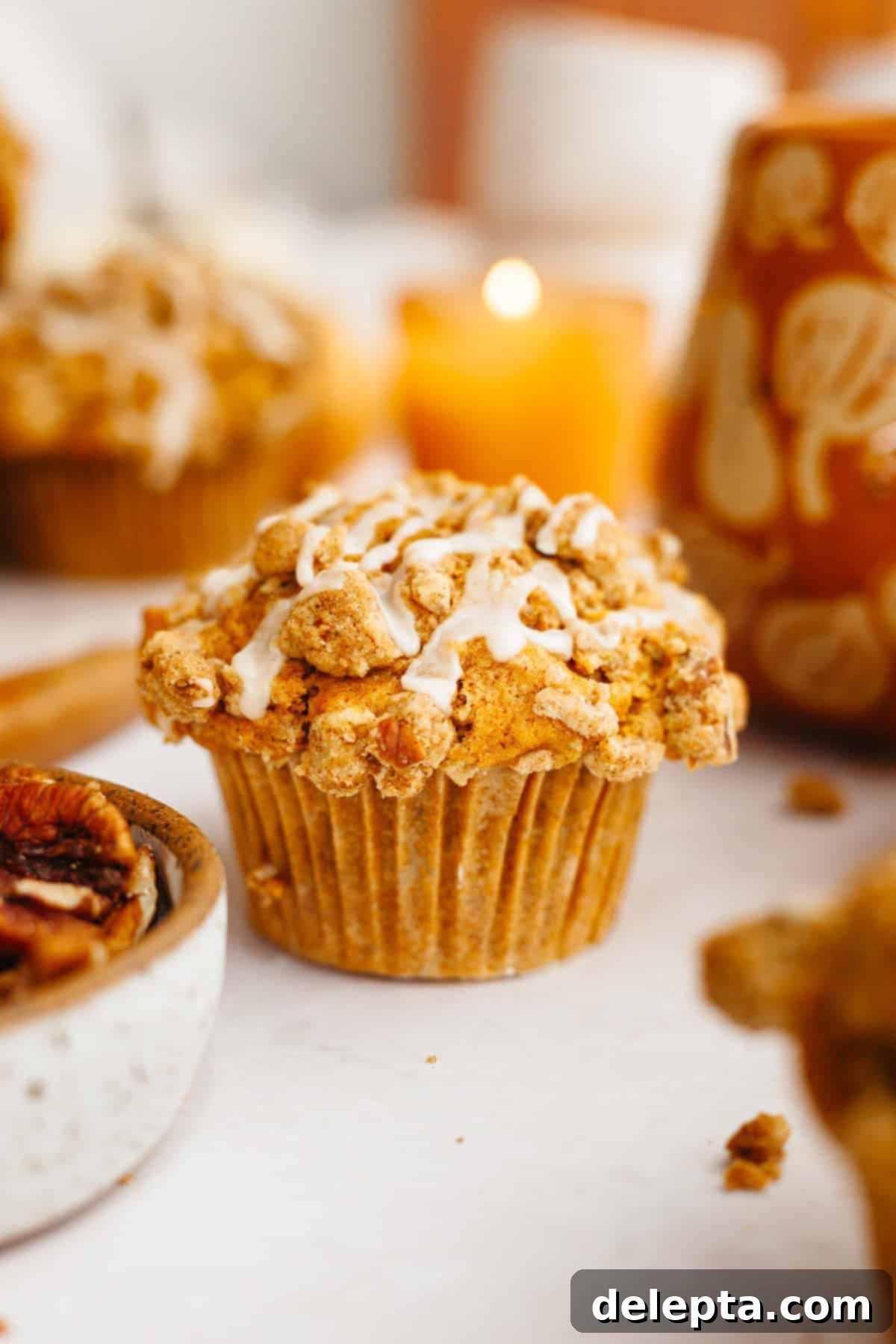 Harvest Pumpkin Pecan Crunch Muffins 2 A close up of a pumpkin pecan muffin with a pecan streusel and a delicate drizzle of maple espresso glaze, showcasing its soft interior.