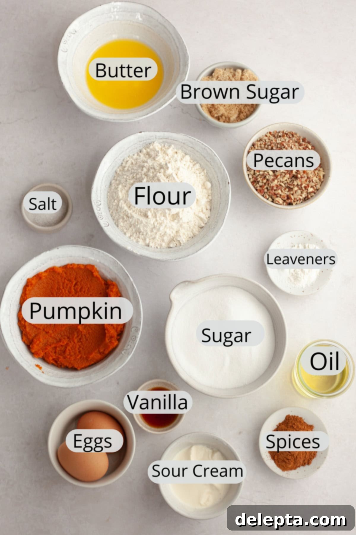Harvest Pumpkin Pecan Crunch Muffins 3 A collection of fresh ingredients laid out, including pumpkin puree, pecans, eggs, sour cream, flour, sugar, and various spices, ready for making pumpkin pecan muffins.