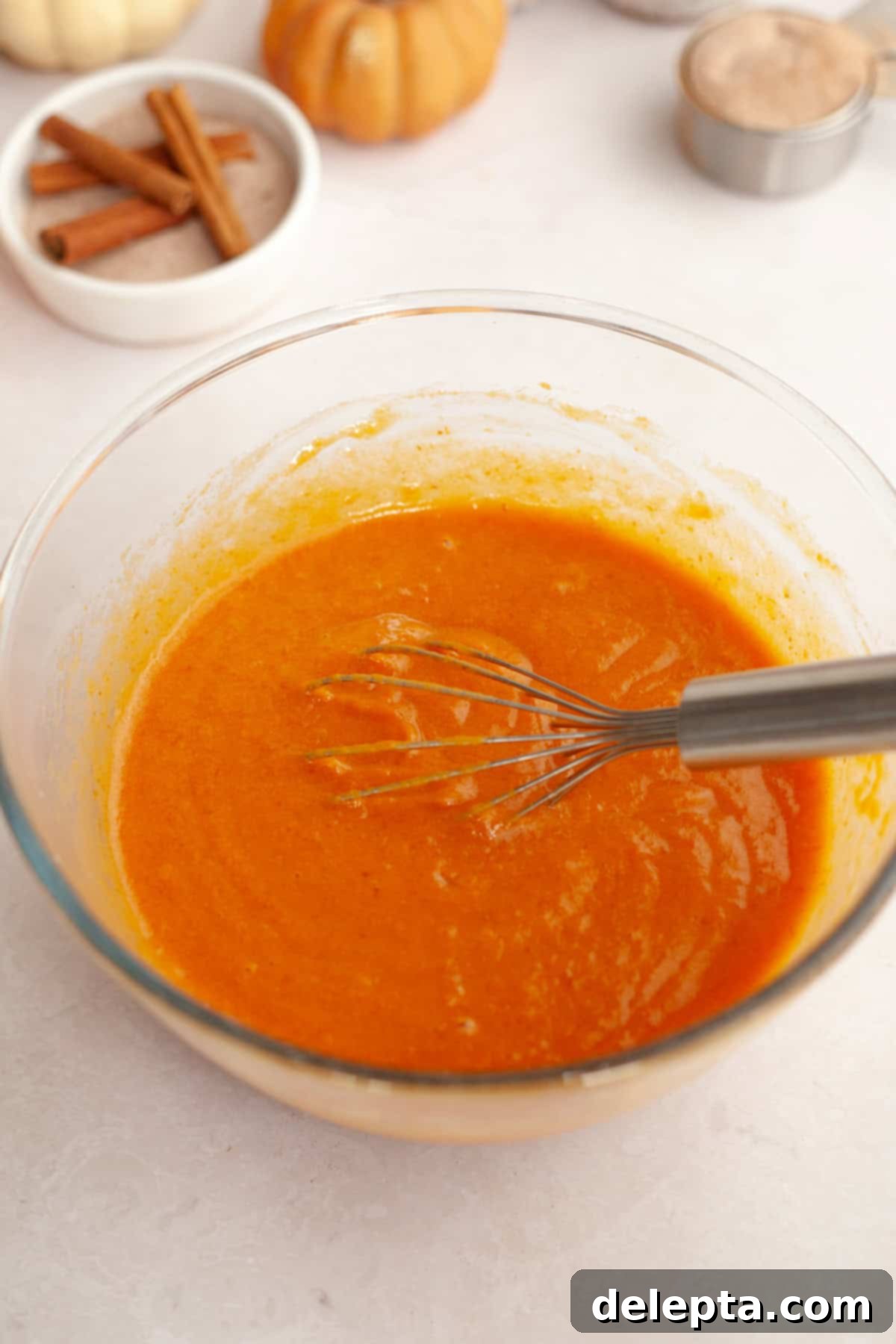 Harvest Pumpkin Pecan Crunch Muffins 5 Pumpkin muffin batter in a large glass bowl, showcasing its smooth, orange hue before dry ingredients are added.