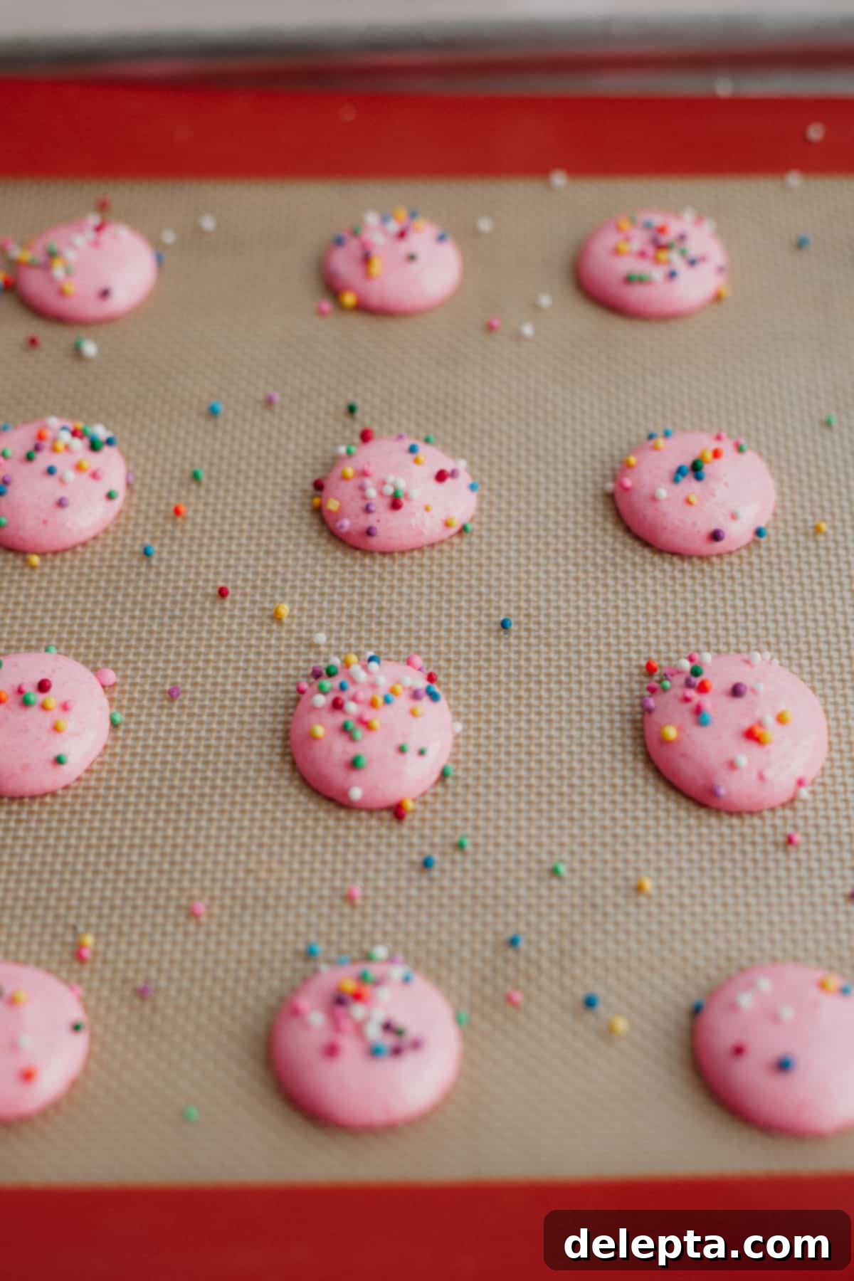Funfetti Macarons 11 Pink macaron shells with sprinkles on top, unbaked