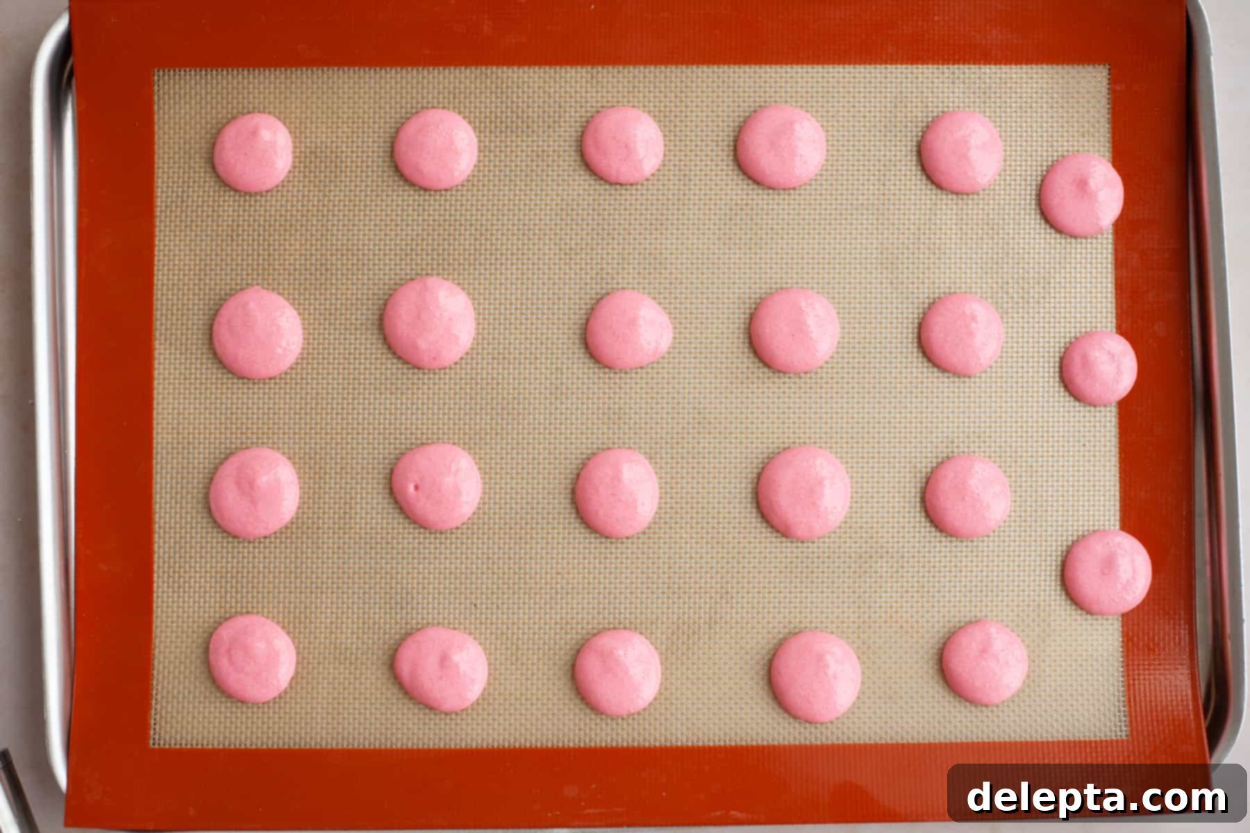 Funfetti Macarons 10 A baking tray with a silpat baking mat and piped out pink macaron shells, unbaked