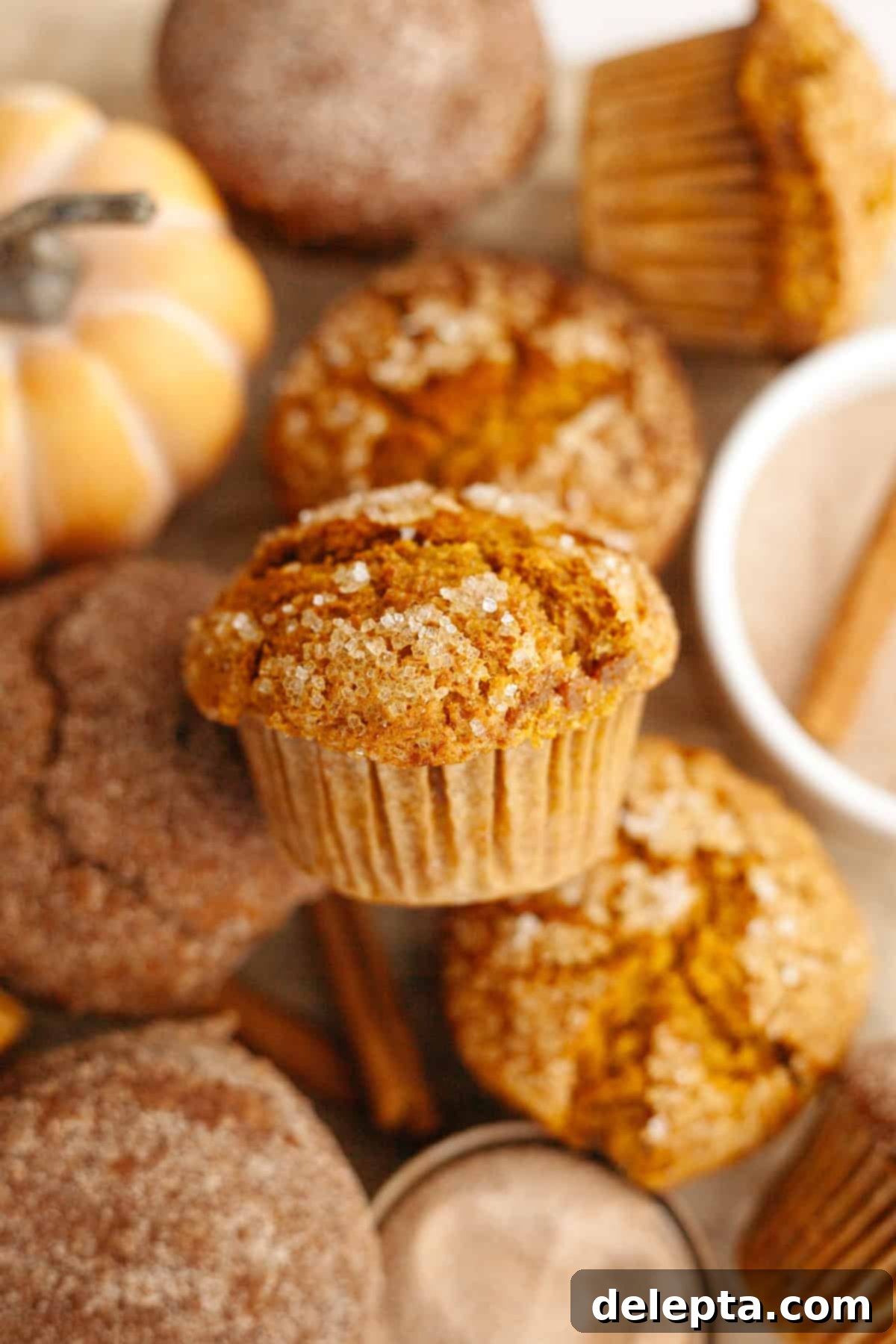 One-Bowl Pumpkin Sour Cream Muffins 7 A close-up shot of baked pumpkin muffins, golden brown and perfectly domed, resting on parchment paper after cooling.