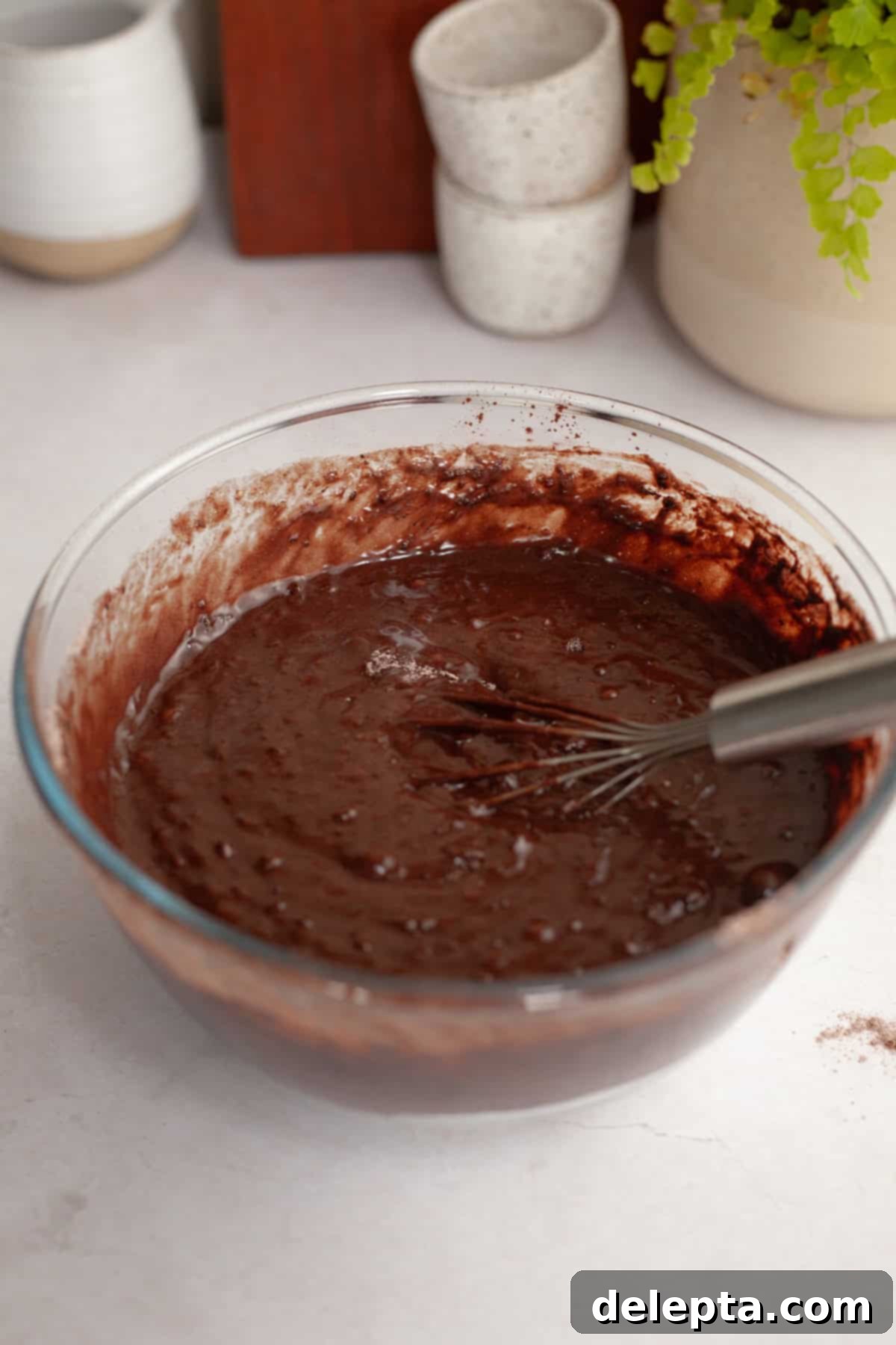 Easy Chocolate Sheet Cake 5 Chocolate cake batter in a glass bowl with a whisk, showing the smooth consistency of the mixture.