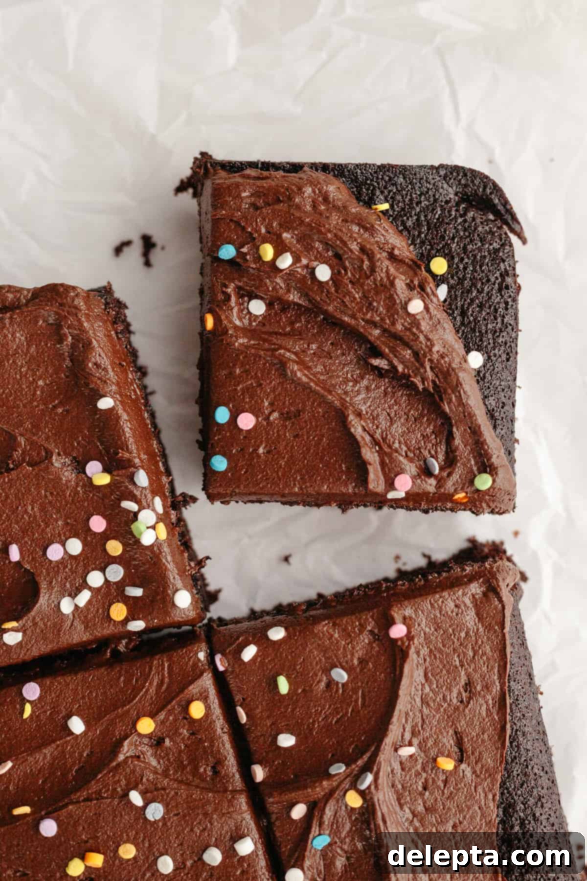 Easy Chocolate Sheet Cake 9 Slices of chocolate sheet cake with chocolate frosting and rainbow sprinkles, arranged on a tray.