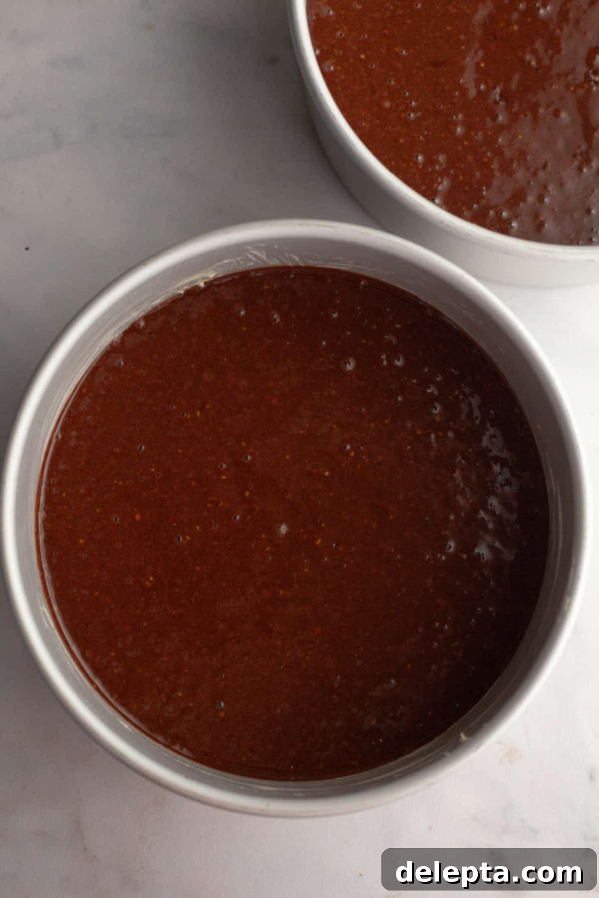 Decadent Chocolate Pistachio Dream Cake 7 Two round cake pans filled with unbaked chocolate cake batter, ready for the oven.