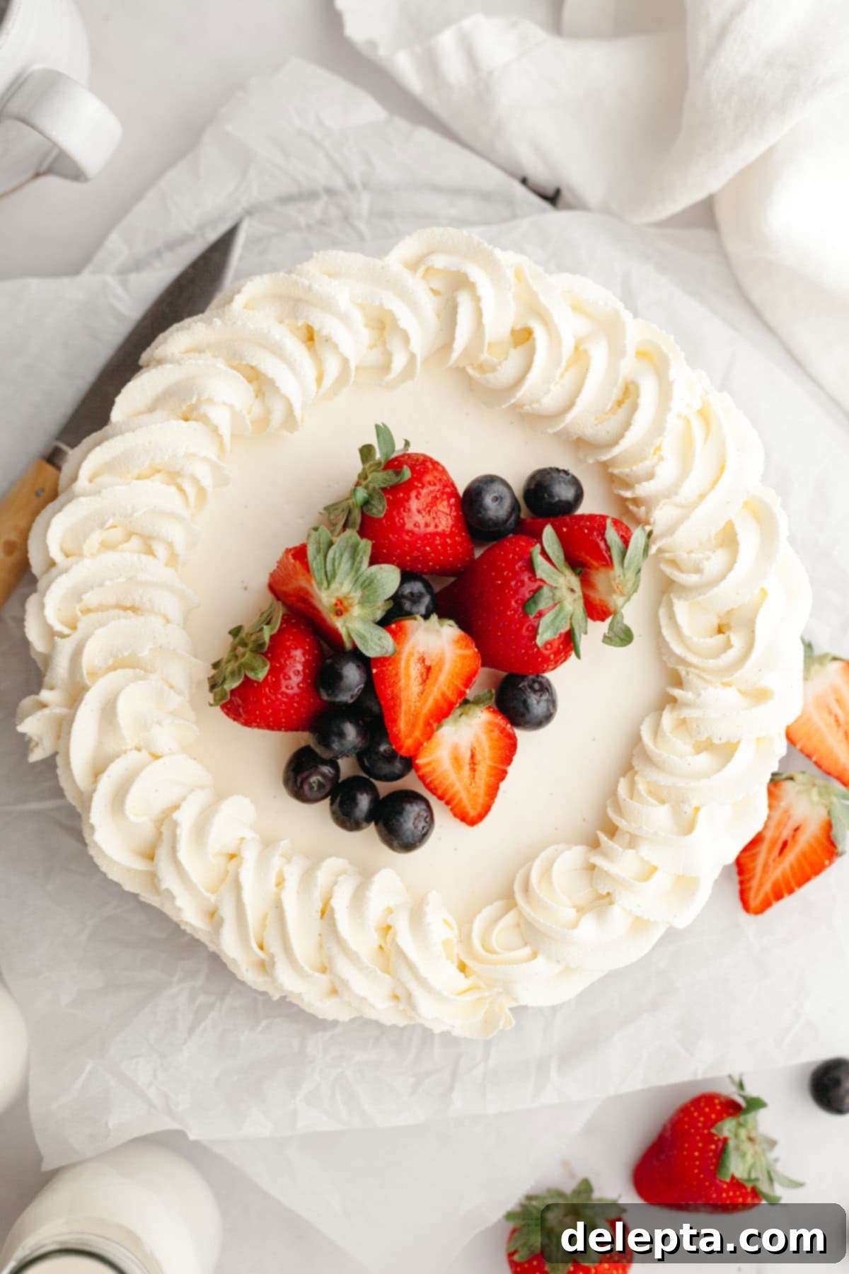 Gelatin-Free No-Bake Vanilla Cheesecake 9 An overhead shot of a vanilla cheesecake piped with whipped cream and decorated with fresh berries.