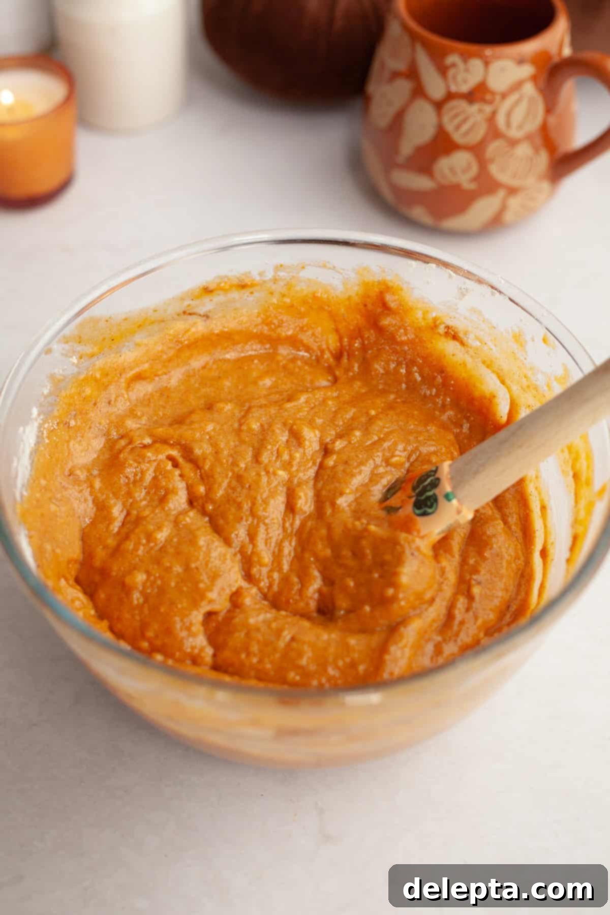 Easy One-Bowl Chocolate Chip Pumpkin Cake 5 Pumpkin cake batter in a glass bowl with a rubber spatula, demonstrating the gentle folding of dry ingredients.