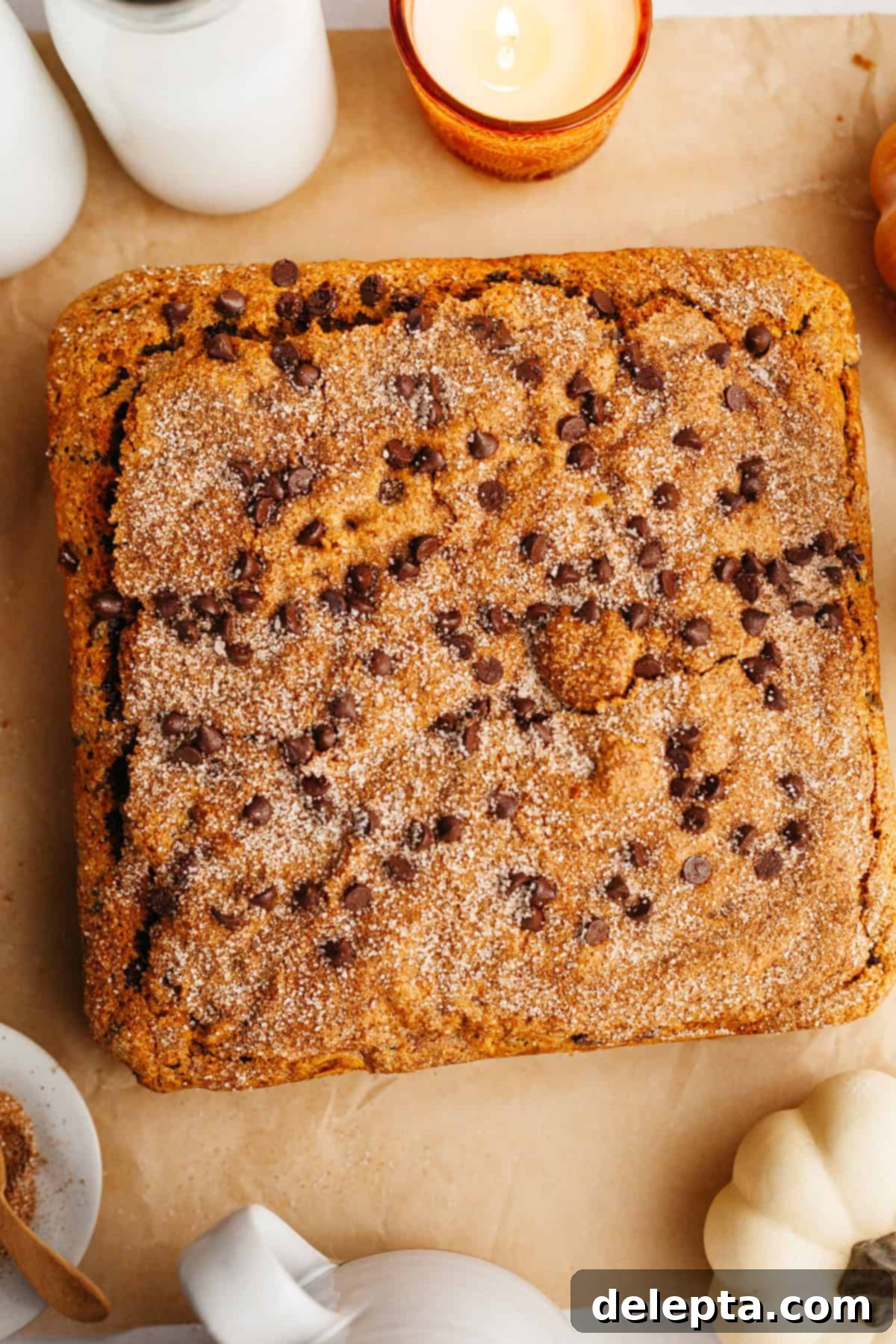 Easy One-Bowl Chocolate Chip Pumpkin Cake 8 An overhead shot of a square chocolate chip pumpkin cake on parchment paper, ready to be sliced.