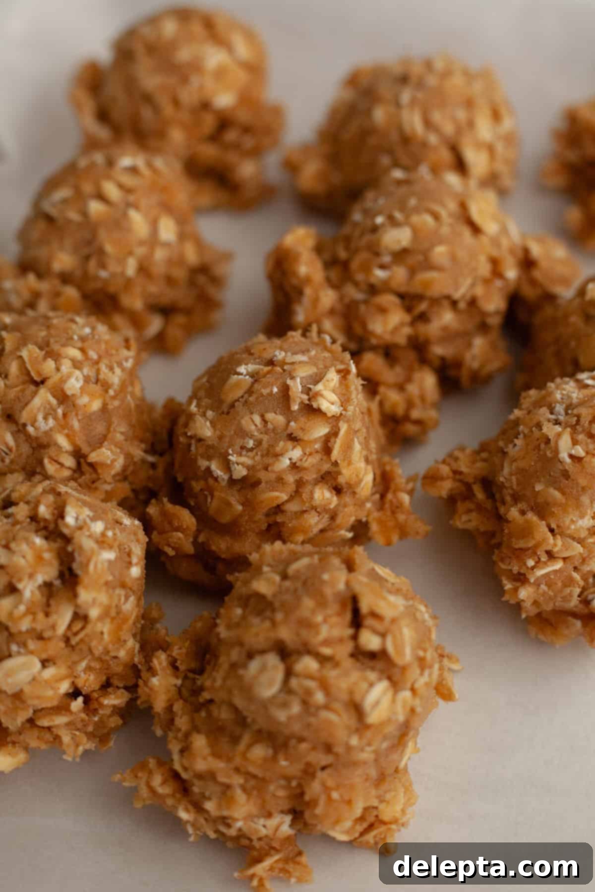 Aromatic Cardamom Oatmeal Cookies with Maple Espresso Glaze 8 Neatly scooped oatmeal cookie dough balls arranged on parchment paper on a baking sheet.