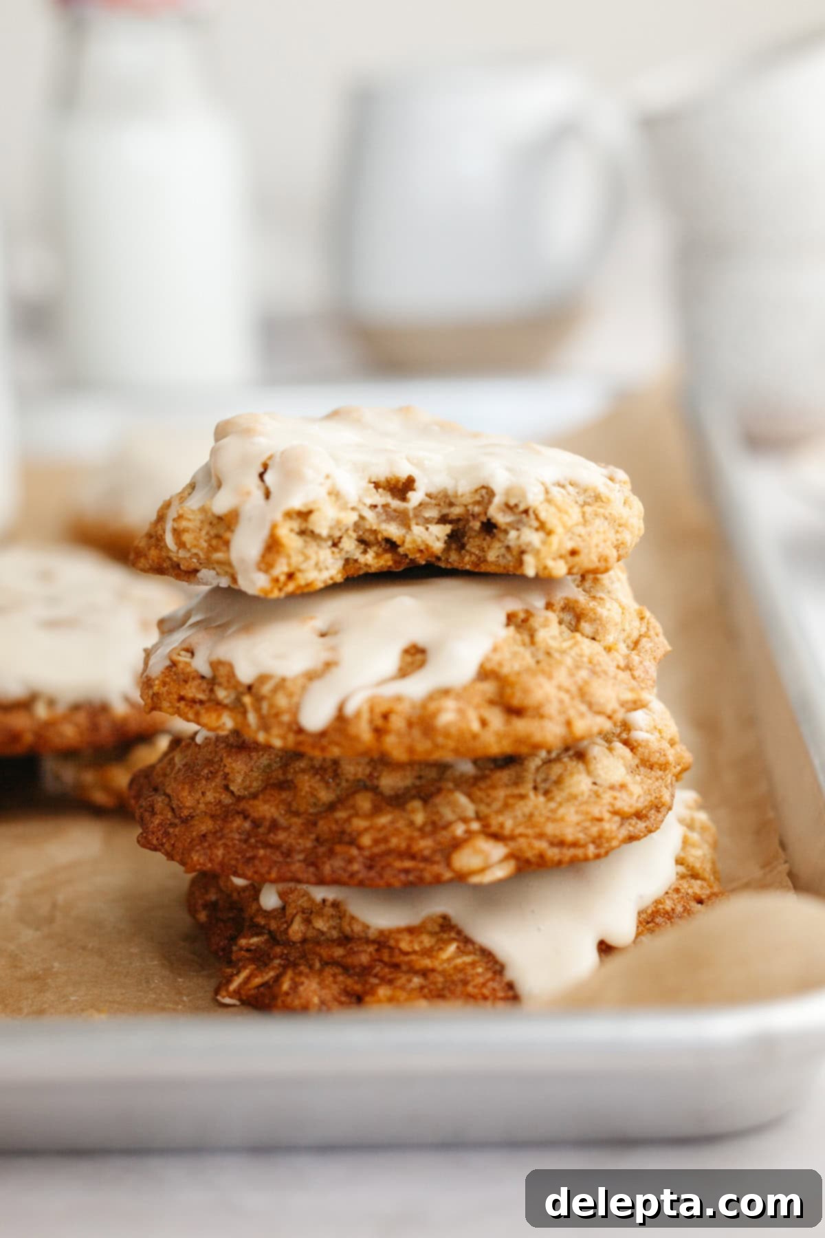 Aromatic Cardamom Oatmeal Cookies with Maple Espresso Glaze 10 A stack of three glistening glazed oatmeal cardamom cookies, with the top cookie having a perfect bite taken out of it, revealing its soft interior.