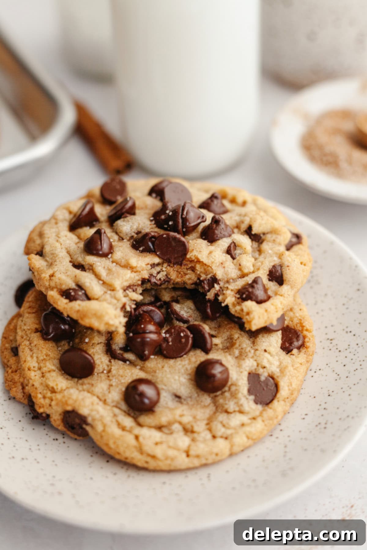 Nutty Brown Butter Chocolate Chip Cinnamon Cookies 11 Two perfectly baked brown butter chocolate chip cinnamon cookies stacked on a small white plate, ready to be enjoyed.