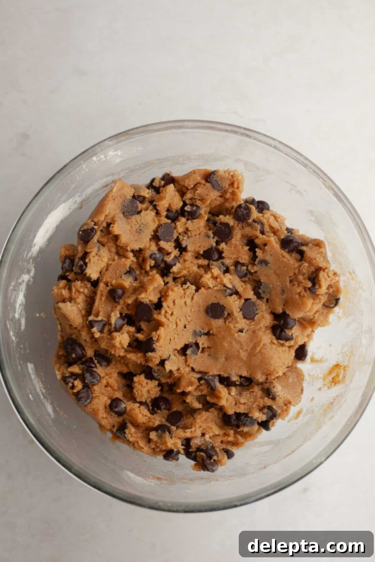 Nutty Brown Butter Chocolate Chip Cinnamon Cookies 8 Chocolate chip cinnamon cookie dough in a glass bowl, with all ingredients mixed, showcasing the distribution of chocolate chips.