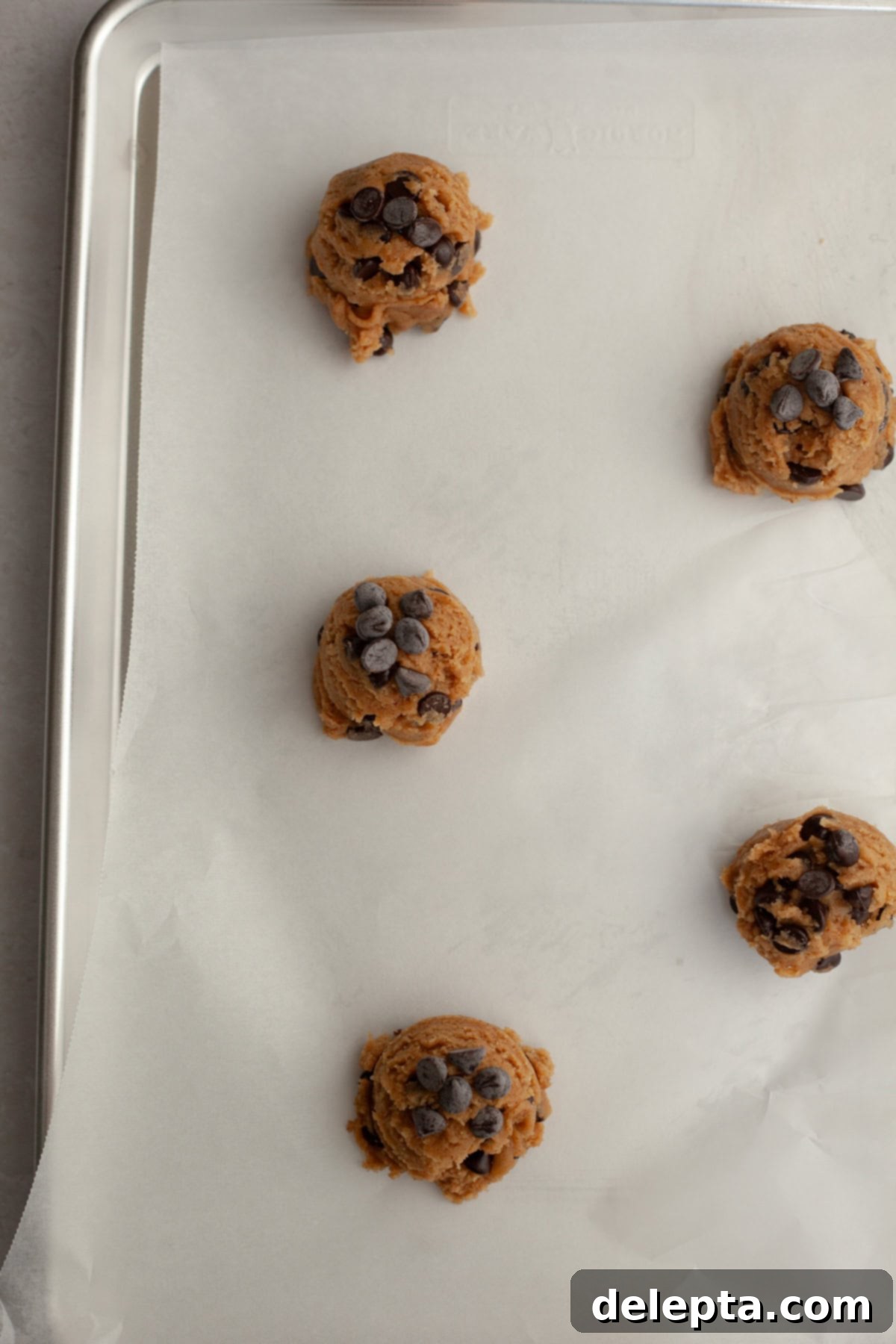 Nutty Brown Butter Chocolate Chip Cinnamon Cookies 9 Perfectly scooped chocolate chip cinnamon cookie dough balls arranged on a parchment-lined baking sheet, ready for baking.