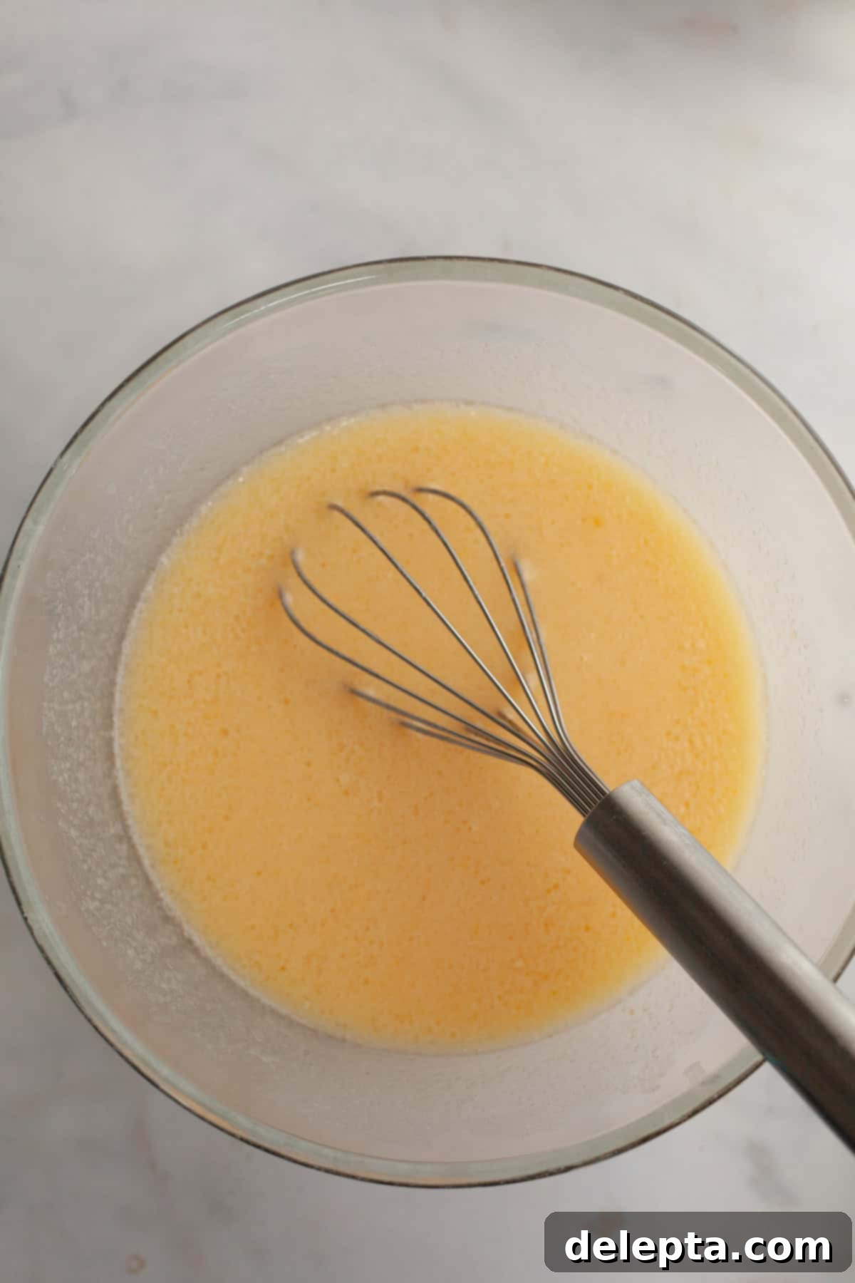 Bite-Sized Cinnamon Bliss 4 Melted butter, eggs, and sugar in a bowl with a whisk.