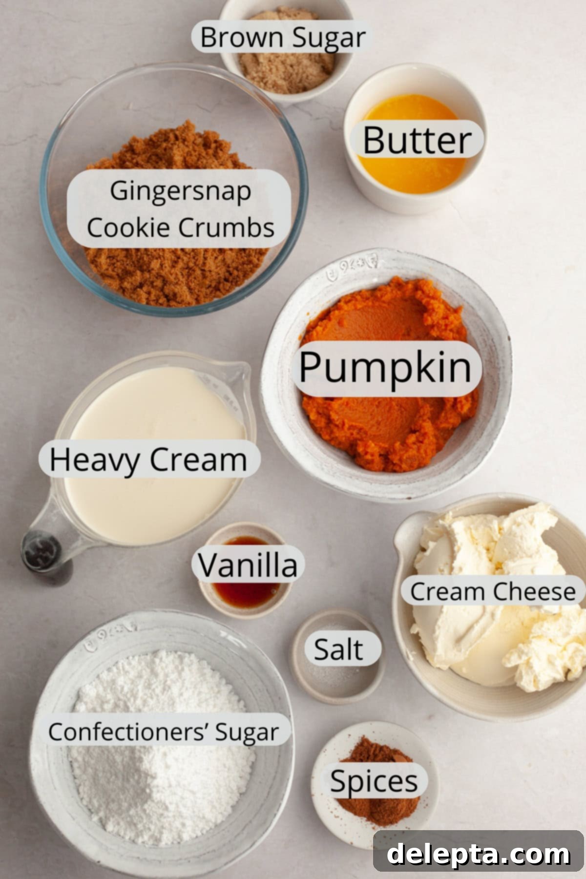 Spiced No-Bake Pumpkin Cheesecake Bars 3 All the ingredients needed to make pumpkin cheesecake bars, weighed out into small bowls, showcasing fresh pumpkin puree, cream cheese, and gingersnap cookies.