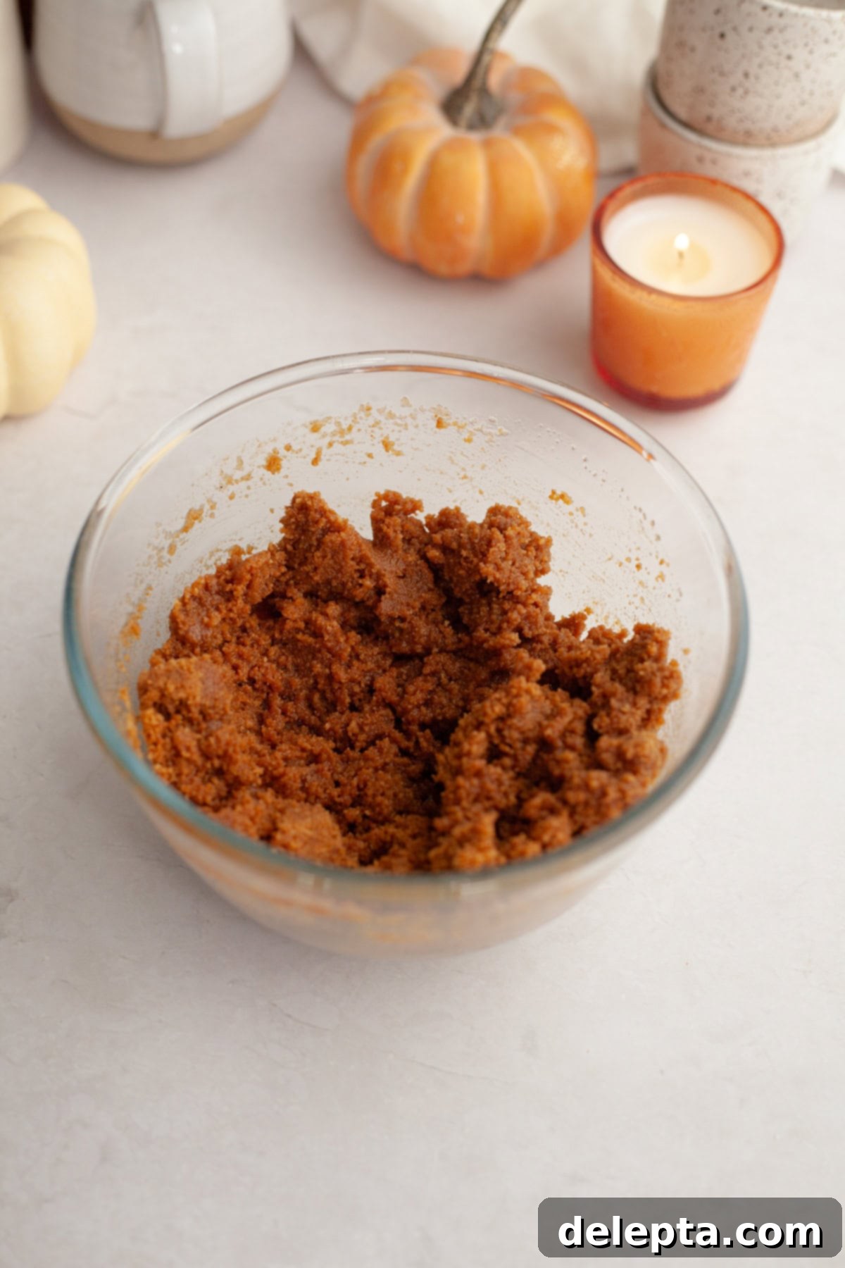 Spiced No-Bake Pumpkin Cheesecake Bars 4 A small glass bowl with gingersnap cookie crumbs and melted butter, ready to be mixed for the crust.