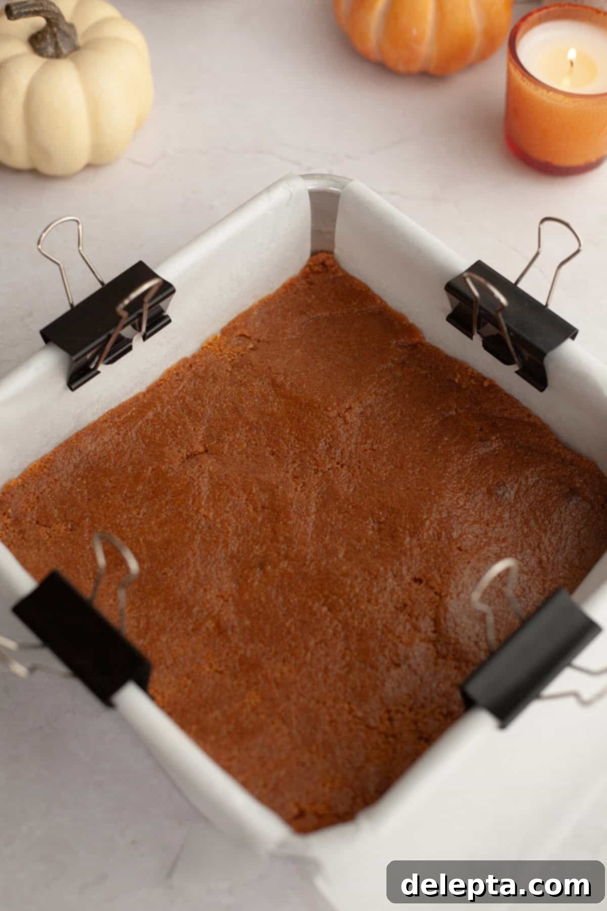 Spiced No-Bake Pumpkin Cheesecake Bars 5 A square baking pan with a firmly pressed gingersnap cookie crust, ready for freezing.