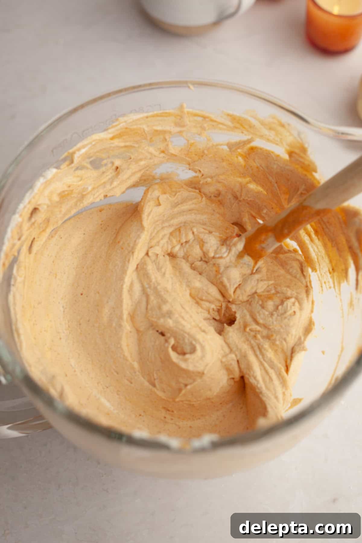 Spiced No-Bake Pumpkin Cheesecake Bars 8 Pumpkin cheesecake filling in a glass bowl, after whipped cream has been gently folded in, showing its light and airy texture.