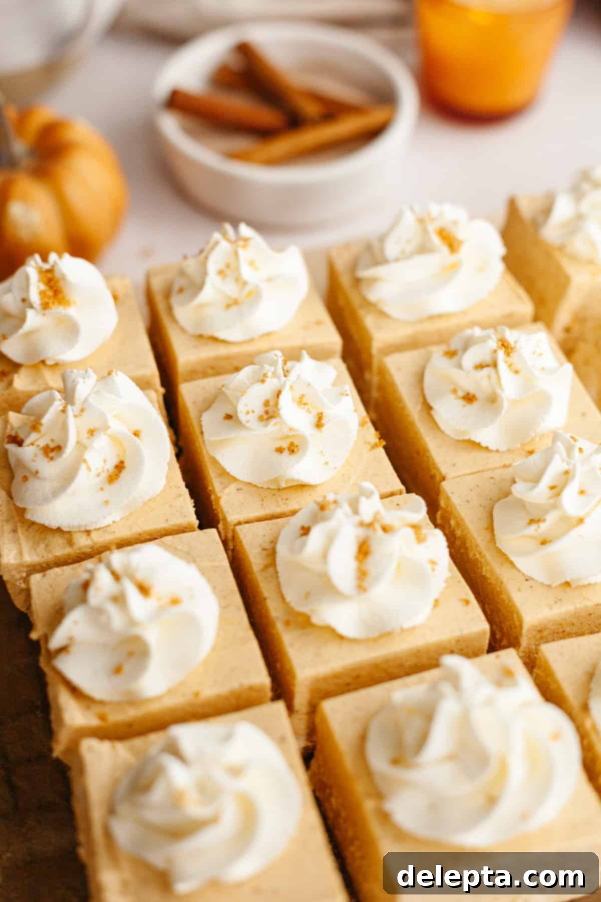 Spiced No-Bake Pumpkin Cheesecake Bars 10 Square slices of pumpkin no bake cheese topped with elegant swirls of whipped cream, invitingly presented.