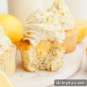 Sunshine Lemon Poppy Seed Cupcakes 12 A close up of a lemon poppy seed cupcake with a bite taken out of it, showing there is lemon curd in the middle of the cupcake.
