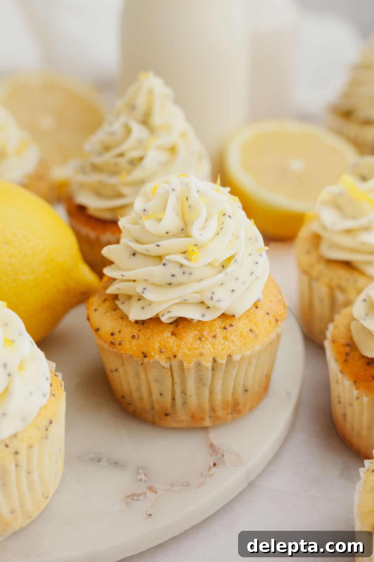 Sunshine Lemon Poppy Seed Cupcakes 10 A vibrant close-up of several frosted lemon poppy seed cupcakes, showcasing the creamy yellow frosting and specks of poppy seeds.